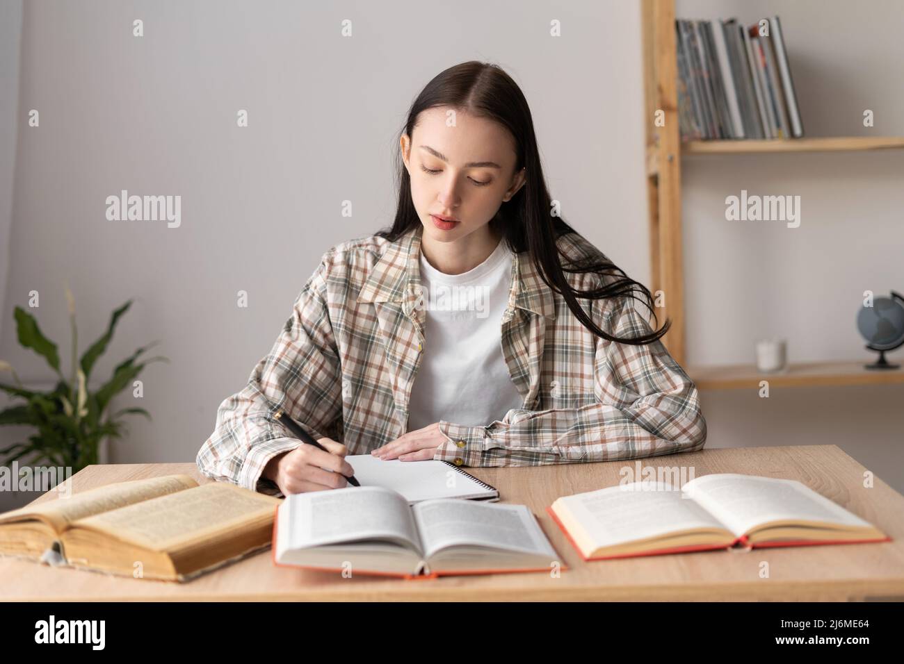 Une étudiante asiatique étudie à distance à la maison en prenant des notes. Les étudiants adolescents apprennent la distance avec des livres faisant leurs devoirs. Banque D'Images