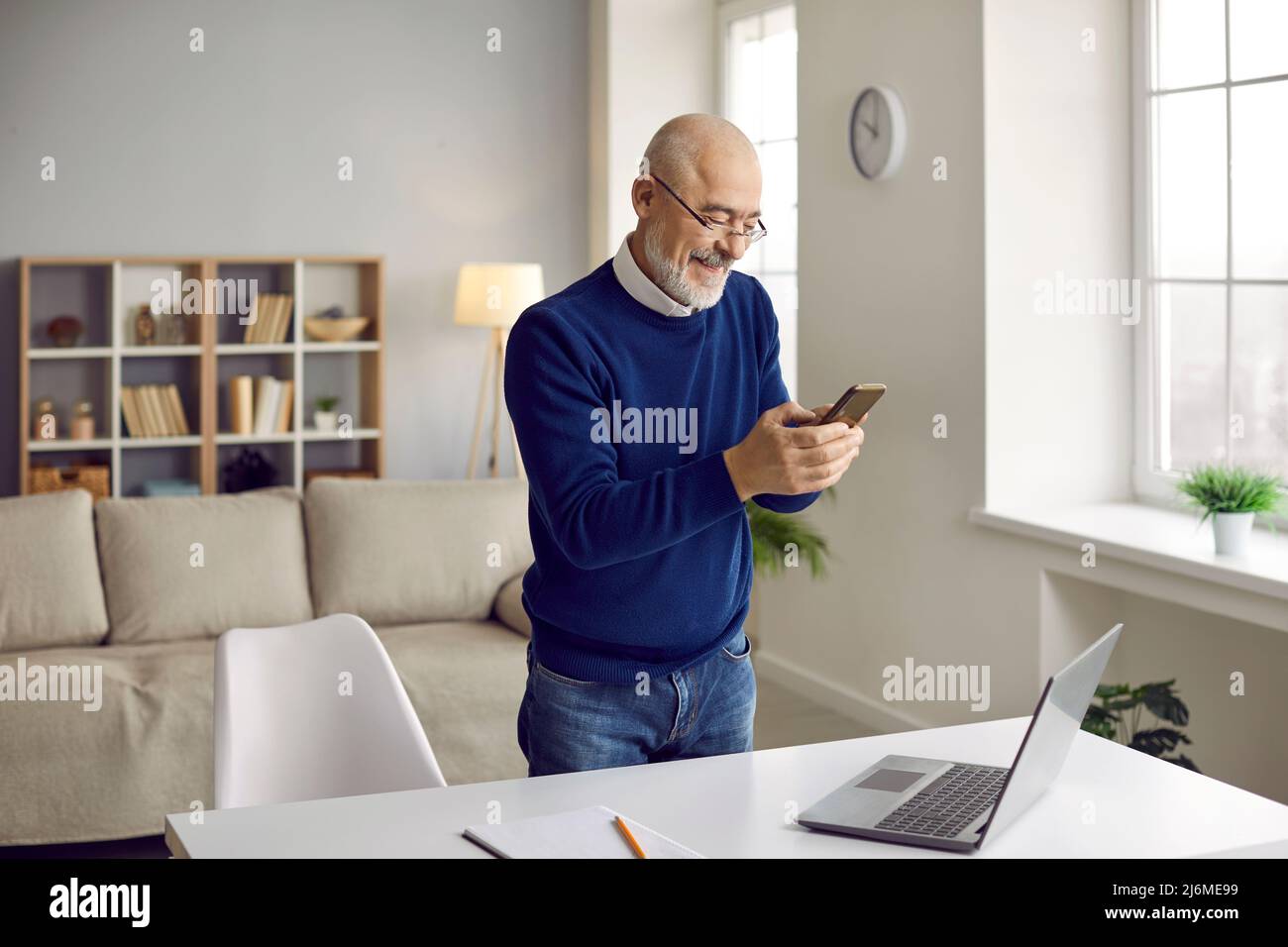 Un homme d'âge moyen travaille sur un ordinateur portable utilise un smartphone Banque D'Images