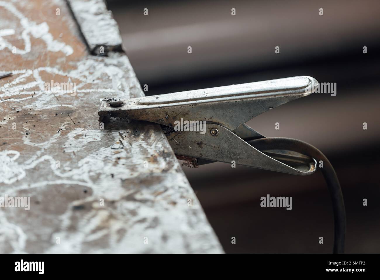 Le fil négatif de la machine à souder avec une broche est fixé à la table métallique. Mise à la terre du concept de sécurité industrielle lors de l'utilisation d'équipements. Banque D'Images