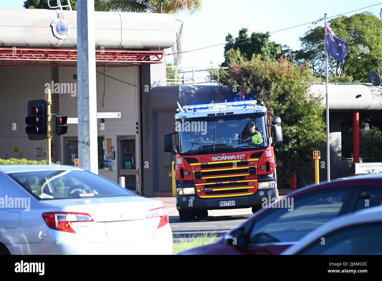 Sauvetage d'incendie à bord d'un camion d'incendie Victoria Scania P310, vu à travers la circulation, car il quitte la caserne d'incendie FRV 32 avec des feux de détresse clignotants Banque D'Images