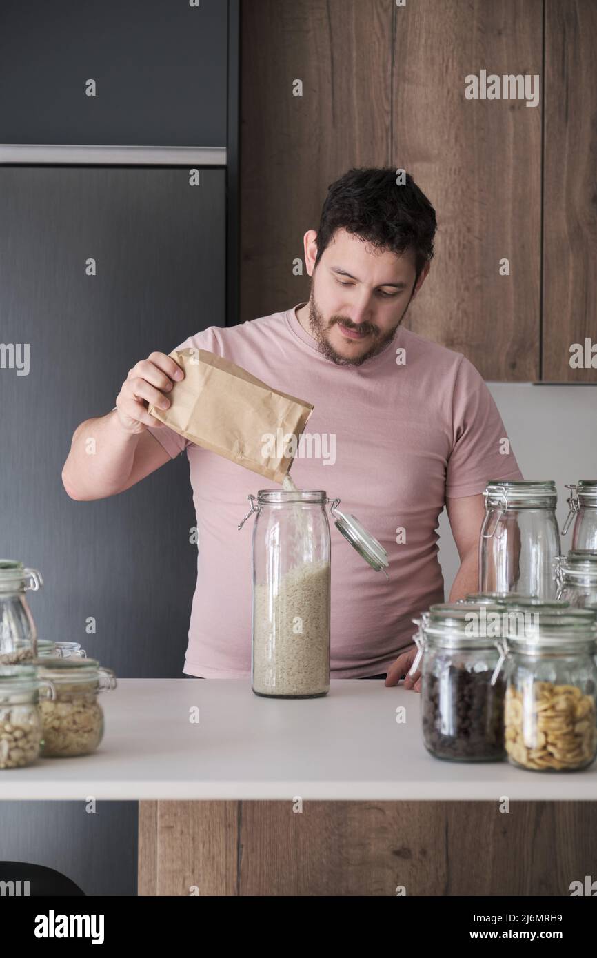 Un jeune latino remplit un pot de riz basmati dans un sac en papier. Banque D'Images