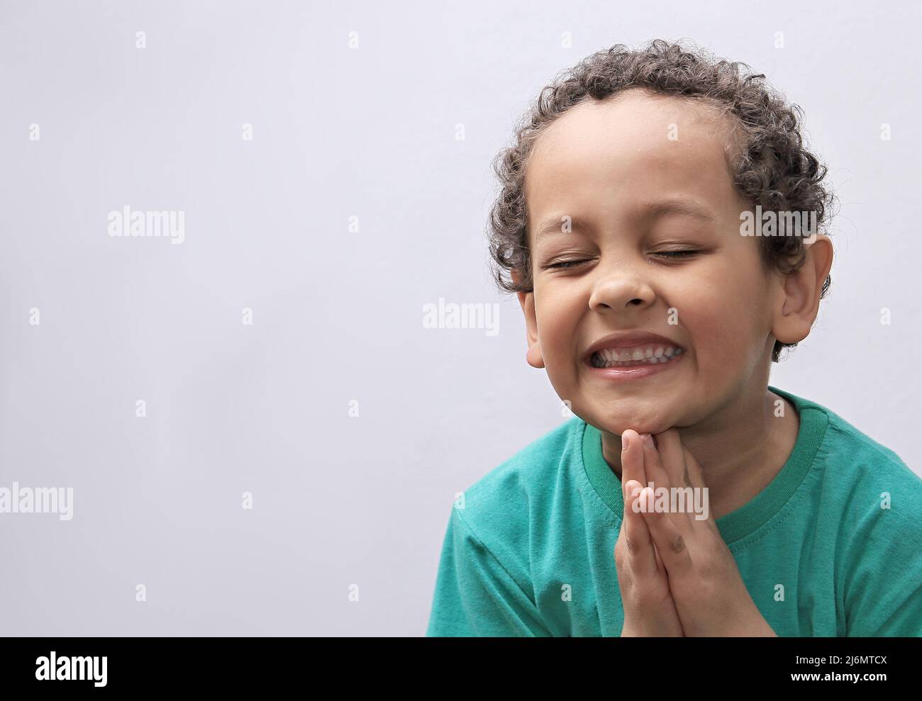 Petit garçon priant à Dieu avec les mains avec la photo de fond noire Banque D'Images