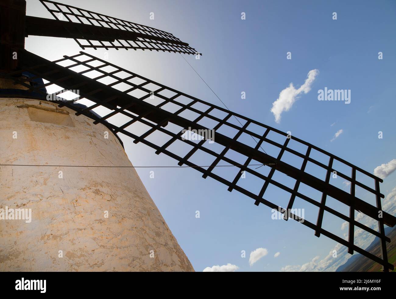Une vue sur les pales d'un moulin à vent silhoueté contre le ciel bleu et la lumière du soleil dans le village castillan de Consuegra à Tolède, Espagne. Banque D'Images