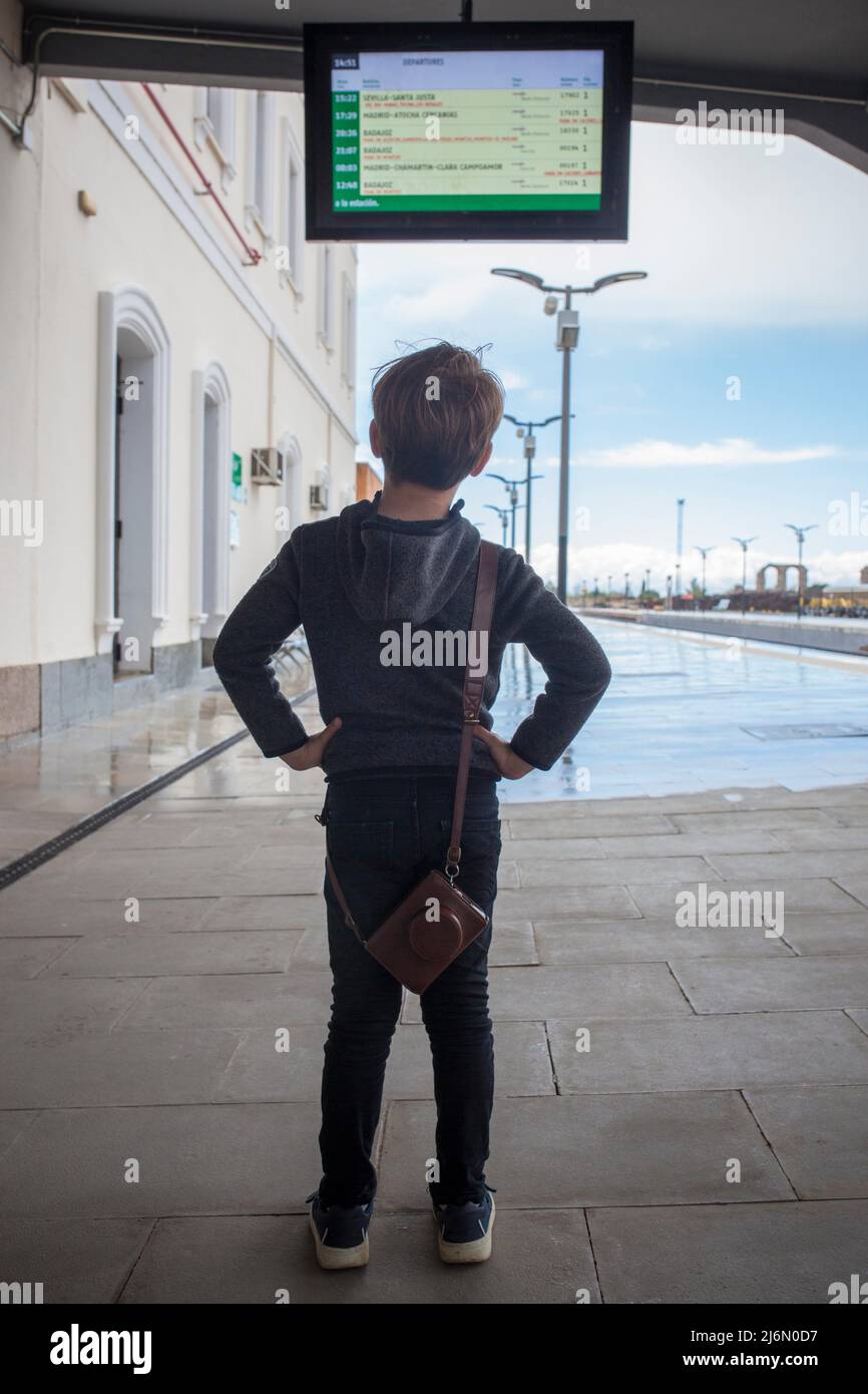 Enfant garçon à la gare regardant le moniteur de départ. Voyage en train avec enfants concept. Banque D'Images