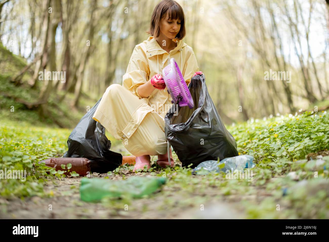 Femme collectant des déchets de plastique éparpillés dans les bois Banque D'Images