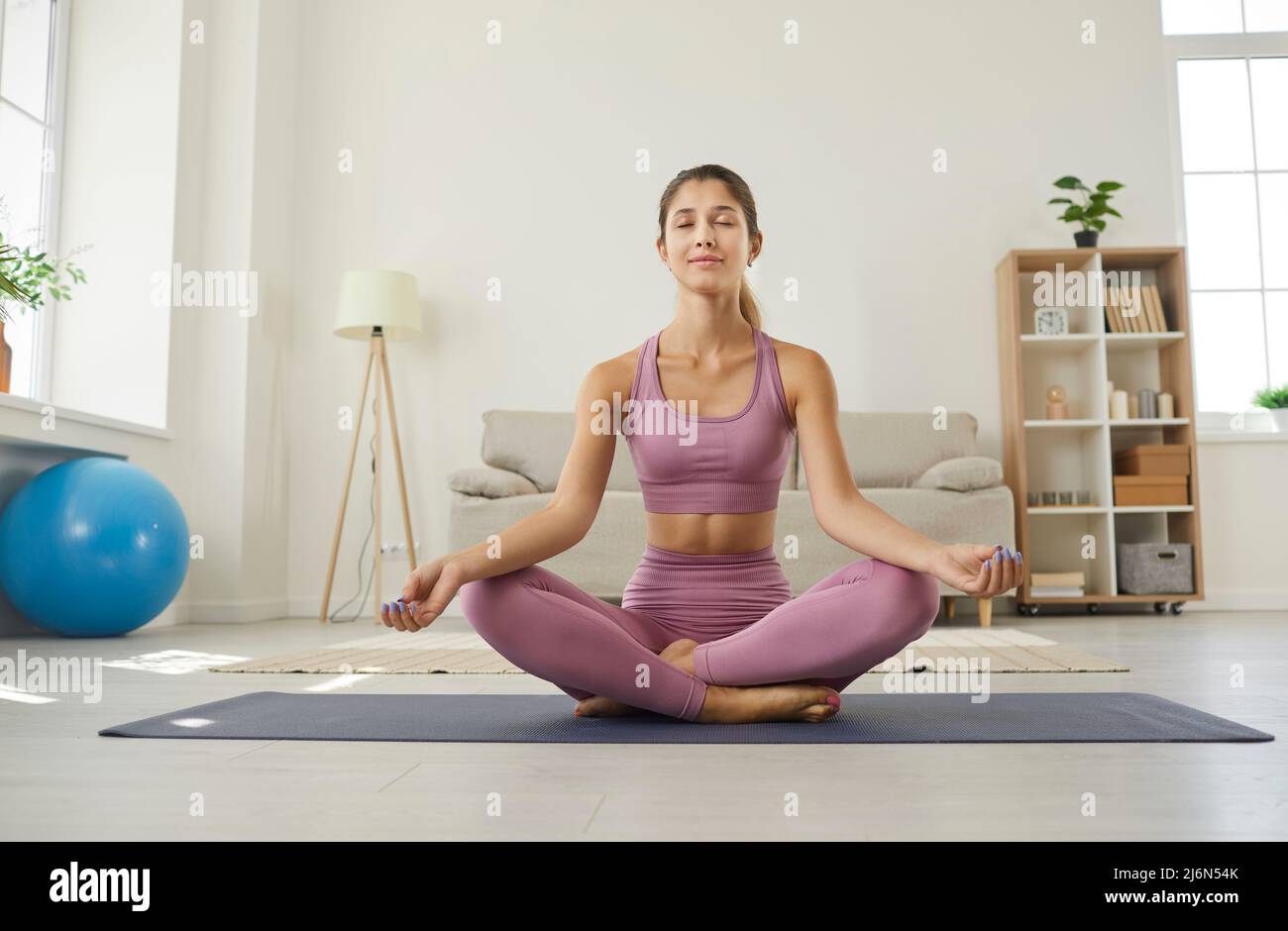 Portrait de la jeune femme yogi détendue et calme heureux méditant tout en faisant de l'exercice à la maison. Banque D'Images