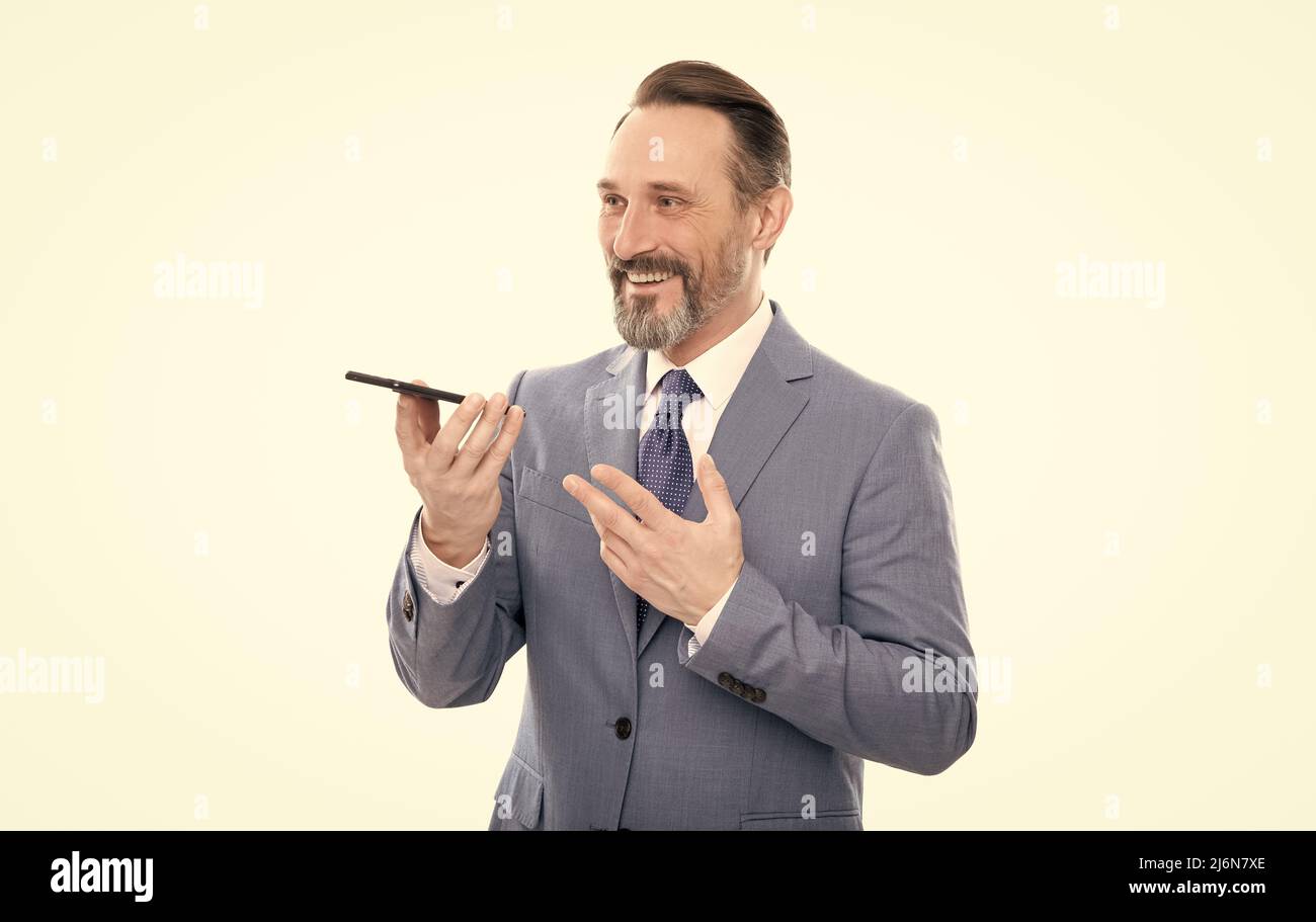 un homme d'affaires souriant et souriant en costume envoie un message vocal sur un téléphone isolé d'un message vocal blanc. Banque D'Images