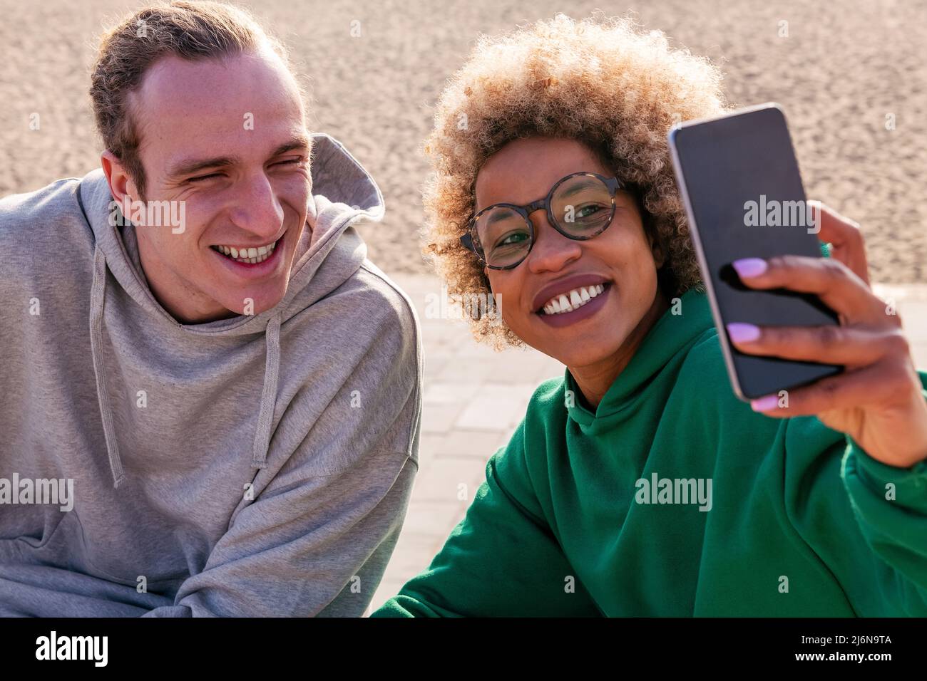 jeune femme latine et homme caucasien souriant tout en prenant une photo de selfie avec le téléphone mobile, concept de style de vie et d'amitié Banque D'Images