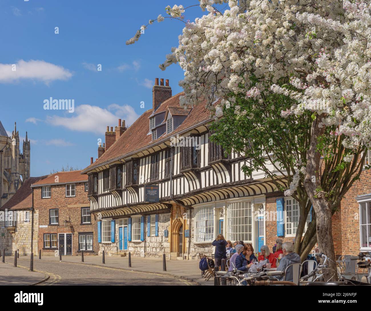 Le soleil se trouve dans un bâtiment historique doté d'une porte très ornée. Un café est en premier plan et une tour est au loin. Banque D'Images