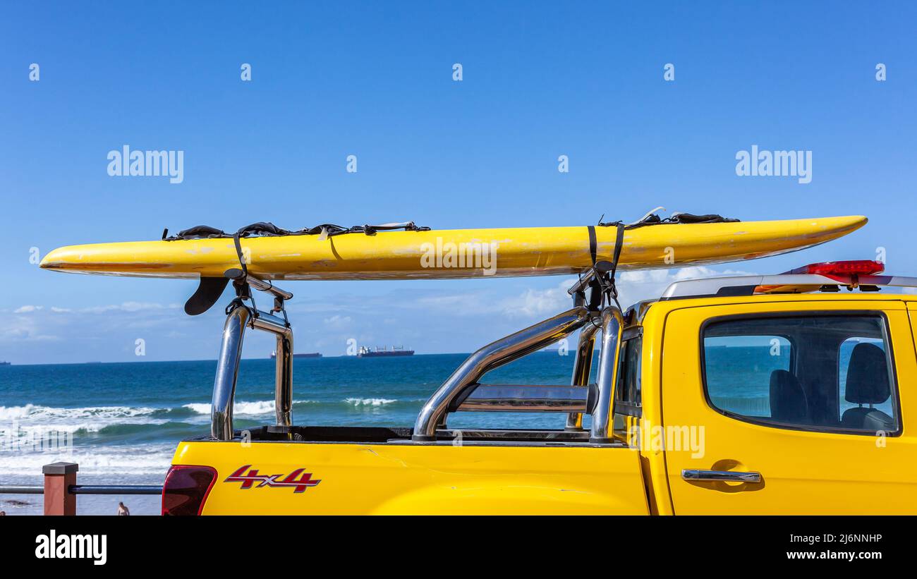 Bateau de sauvetage en gros plan sur l'océan bleu de plage attaché sur un véhicule d'urgence en veille avec des sauveteurs. Banque D'Images