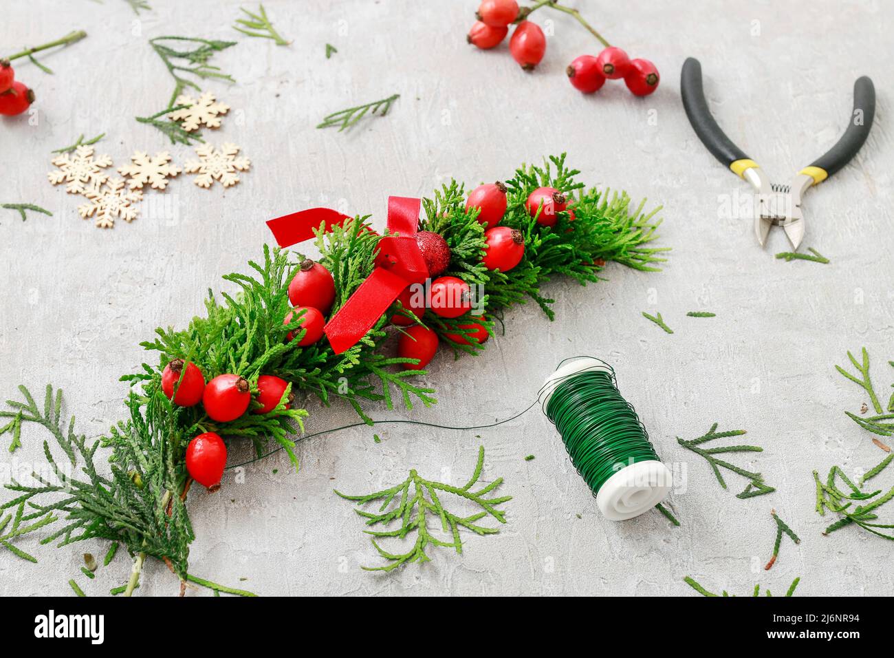Un fleuriste au travail : Comment faire de noël traditionnelle couronne de porte avec thuja brindilles et Wild Rose fruits. Pas à pas, tutoriel. Banque D'Images