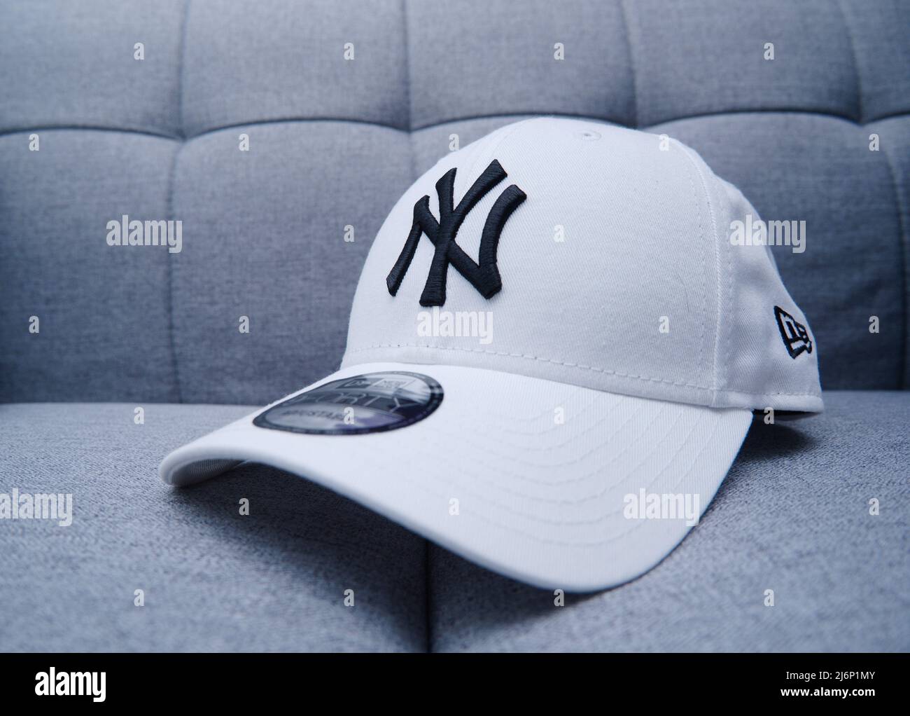 Hong Kong - 3 mai 2022 : casquette de baseball ajustée White New York Yankees pour hommes sur un canapé gris. Avec broderie épaisse et autocollant. Banque D'Images