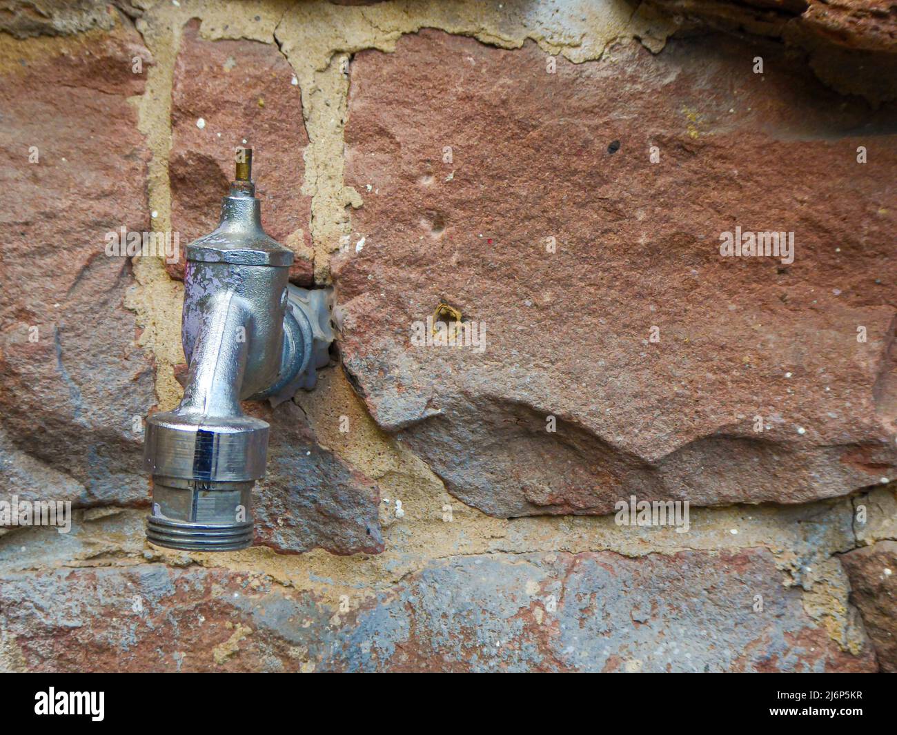 l'ancien robinet d'eau dépasse du mur de grès rustique dans le cadre du système d'irrigation du jardin Banque D'Images