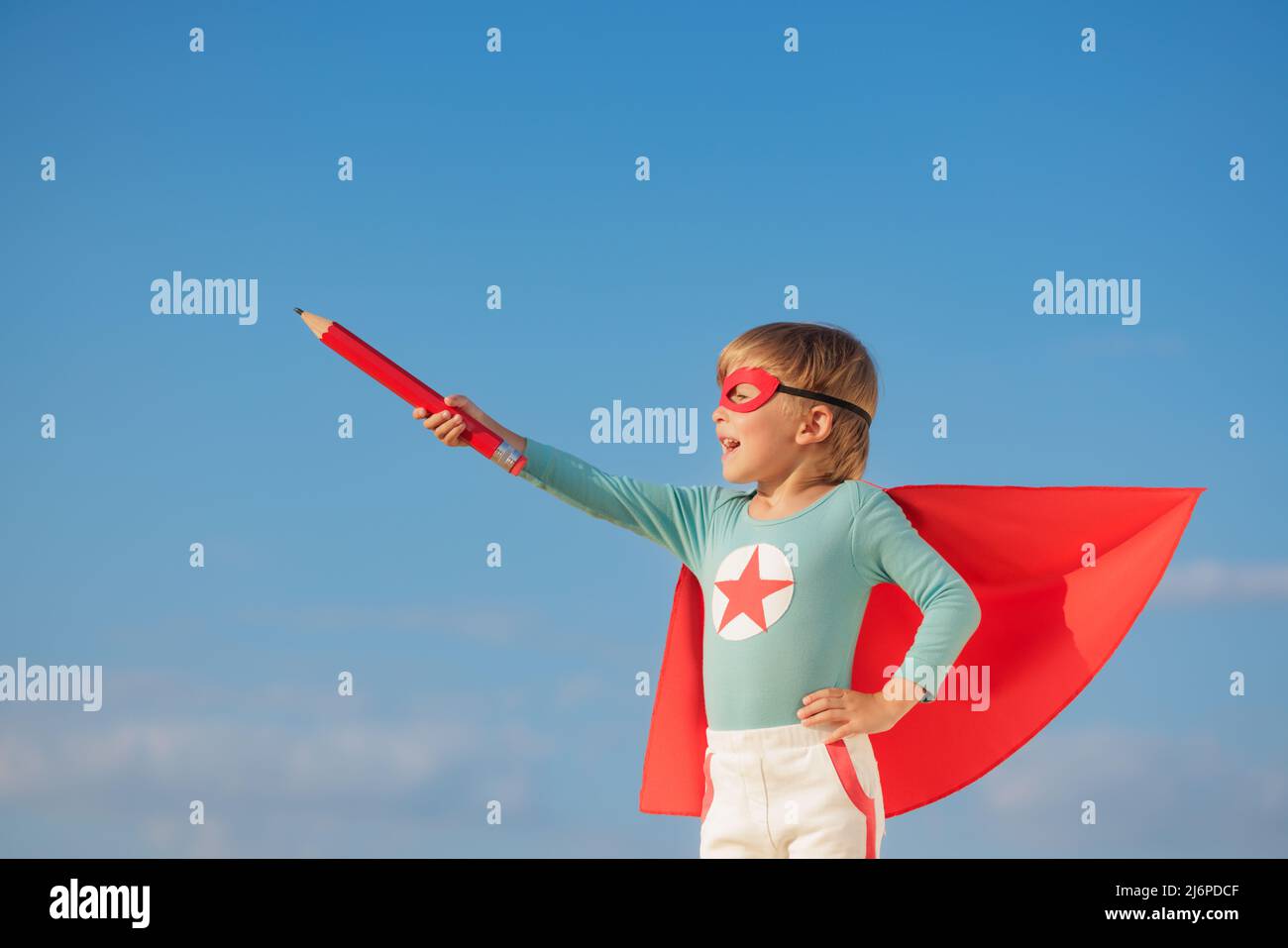 Enfant super-héros jouant à l'extérieur. Super héros Kid contre fond bleu ciel d'été. Imagination et liberté Banque D'Images