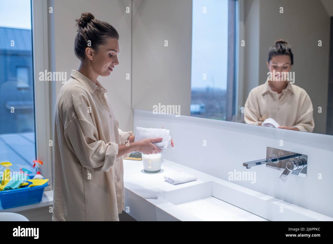 Jeune femme dans la salle de bains faisant un peu de nettoyage Banque D'Images