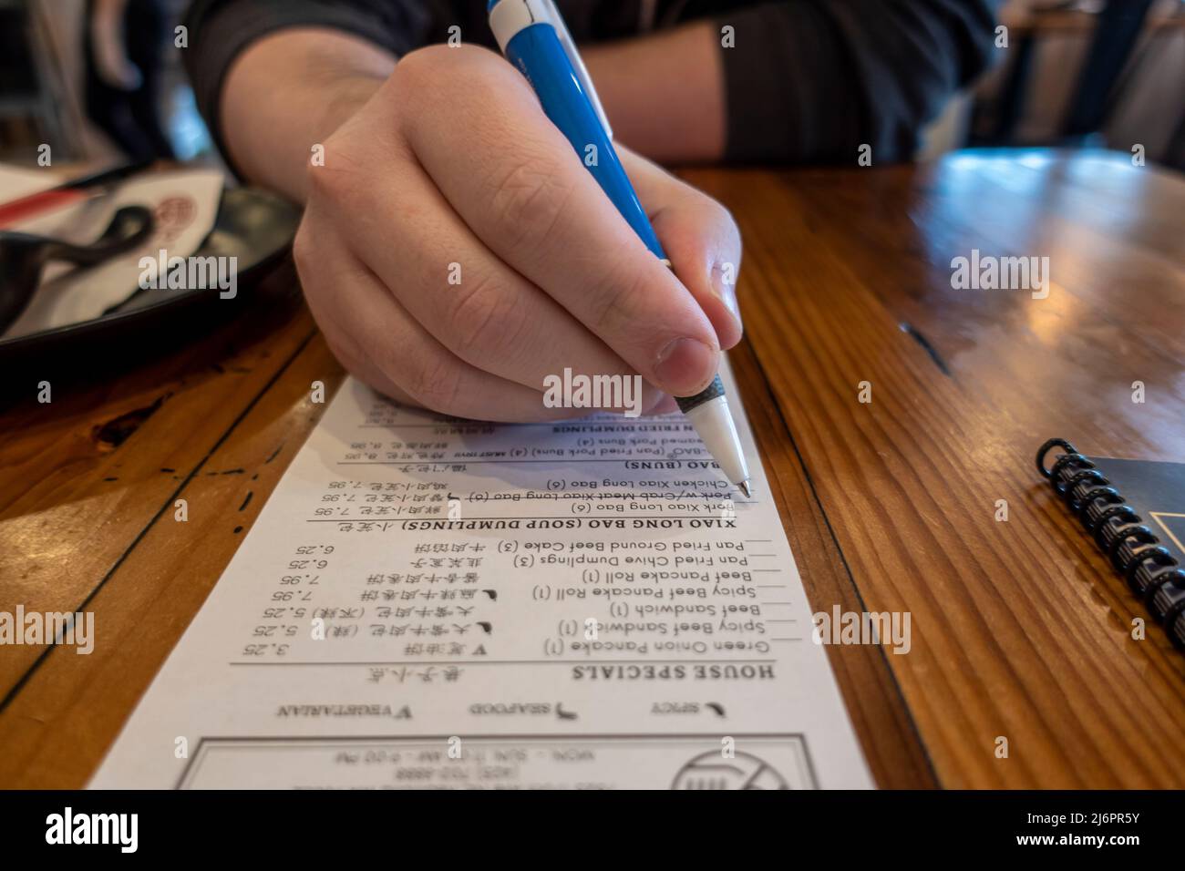 Gros plan, attention sélective sur un homme caucasien tenant un stylo, plaçant sa commande dans un restaurant imposant Banque D'Images