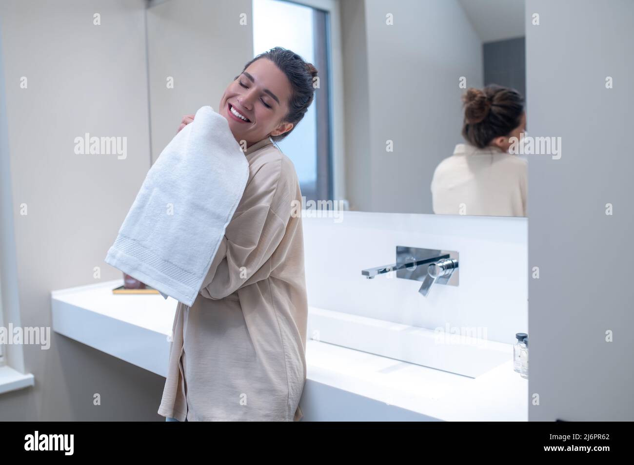 Femme souriante ayant l'air content et tenant une serviette fraîche entre les mains Banque D'Images