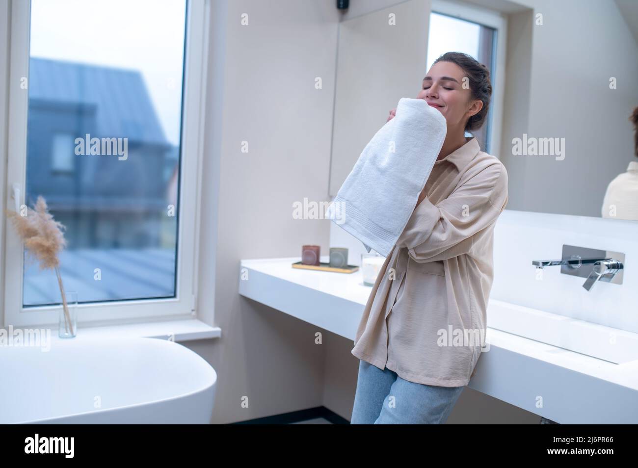 Une femme sent une serviette fraîche après le lavage Banque D'Images