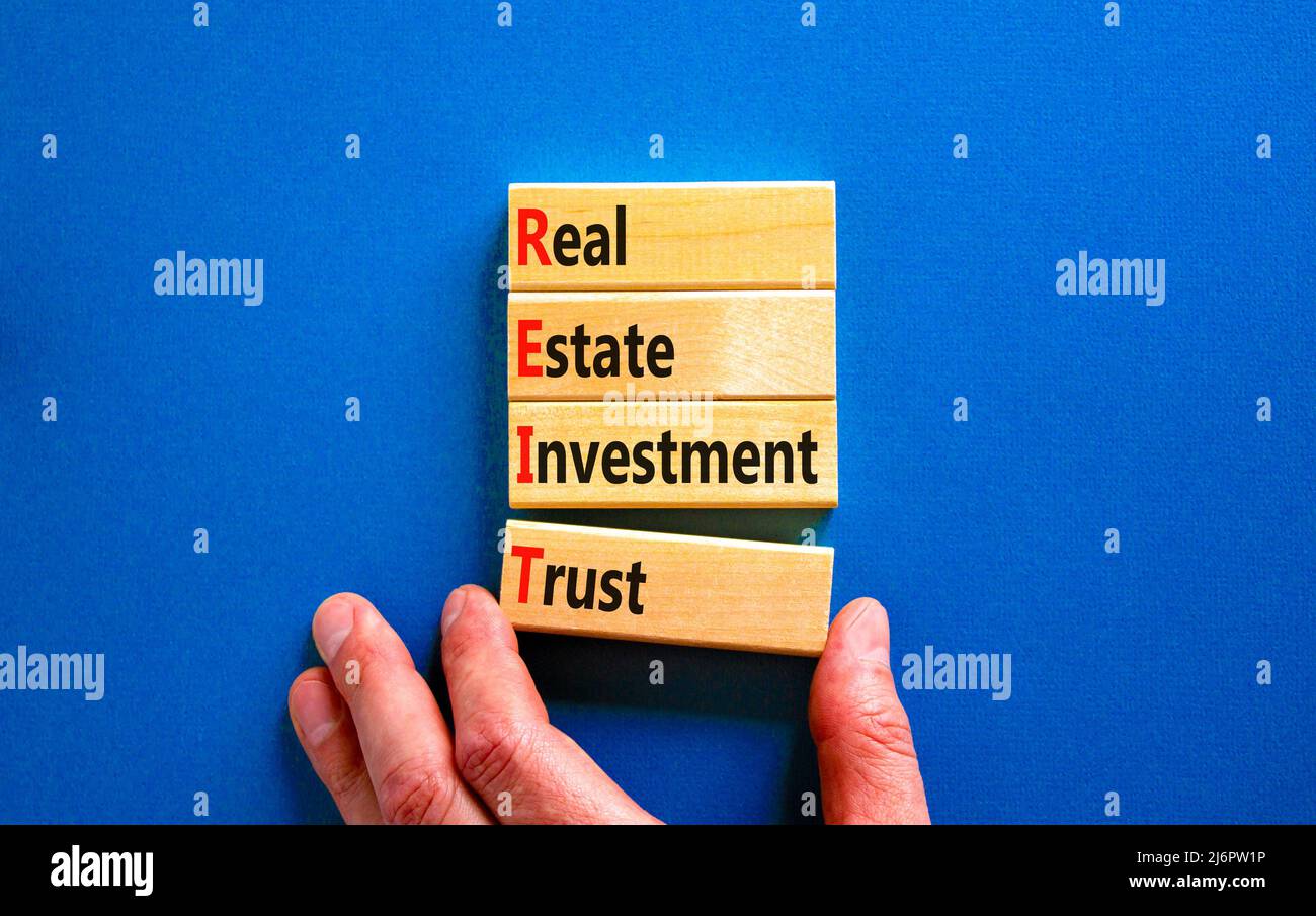 Symbole de fiducie de placement immobilier REIT. Concept mots REIT investissement immobilier confiance sur des blocs de bois sur fond bleu magnifique. Entreprise REIT Banque D'Images