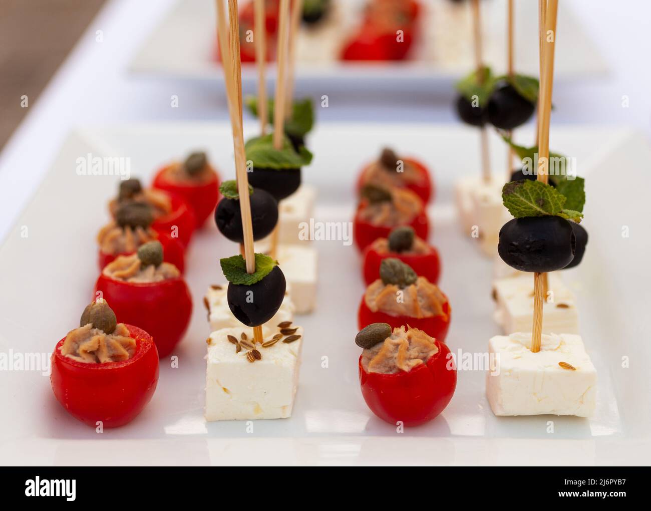 Préparation de délicieux hors-d'œuvre au fromage de chèvre doux avec olives et feuilles de menthe et tomates sauce au thon et câpres pour la fête Banque D'Images