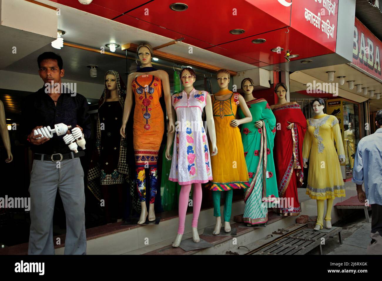 Un homme qui se tient devant une rangée de mannequins, alors qu'il tient des ampoules à l'avant d'un magasin de mode à Varanasi, dans l'Uttar Pradesh, en Inde. Banque D'Images