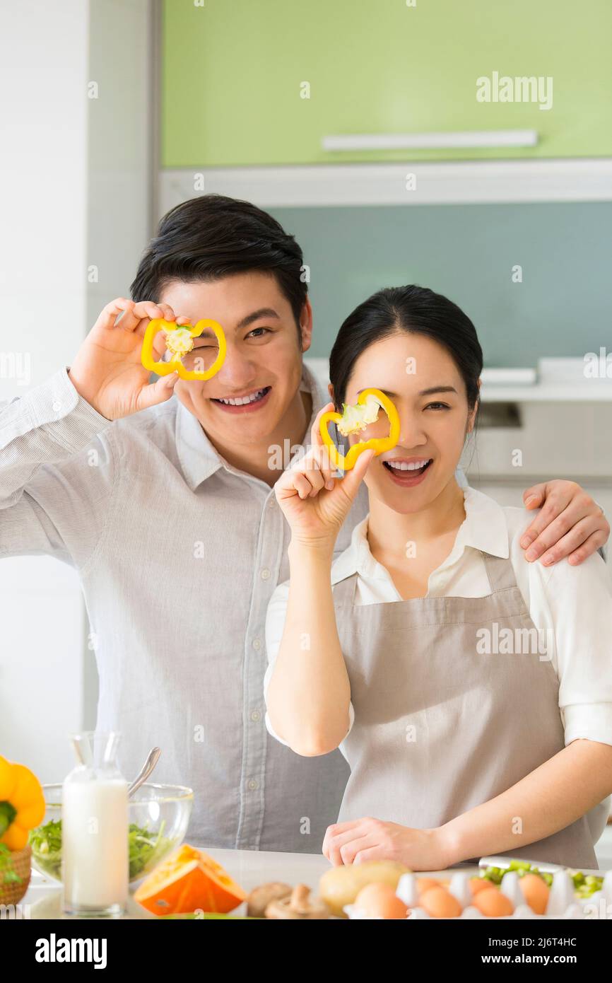 Dans la cuisine familiale, un jeune couple qui apprécie la cuisine ensemble en prenant des tranches de poivron jaune - photo de stock Banque D'Images