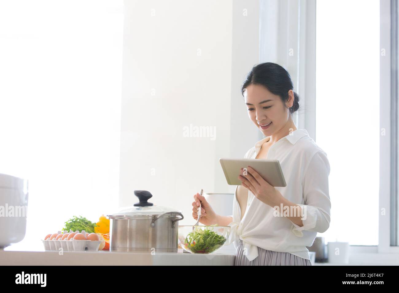 Jeune femme au foyer utilisant une tablette pour prendre des cours de cuisine dans la cuisine familiale - photo de stock Banque D'Images