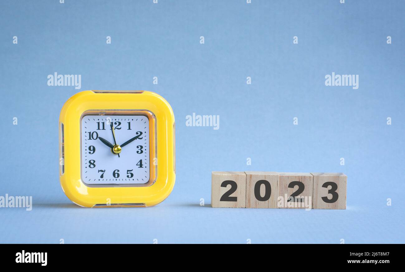 Cube en bois sur une rangée avec texte, 2023 avec une horloge jaune. Concept de la nouvelle année. Banque D'Images