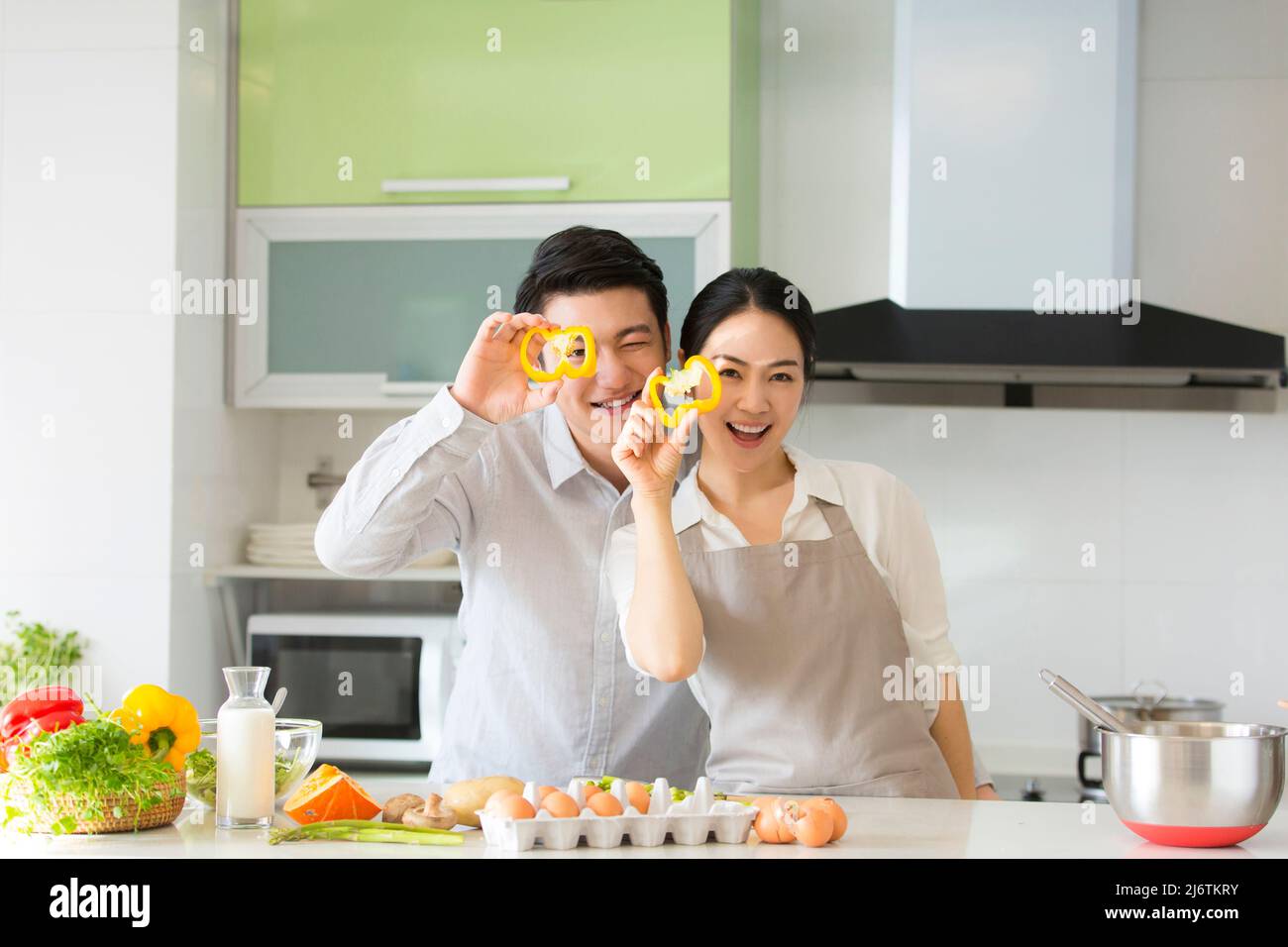 Dans la cuisine familiale, un jeune couple qui apprécie la cuisine ensemble en prenant des tranches de poivron jaune - photo de stock Banque D'Images