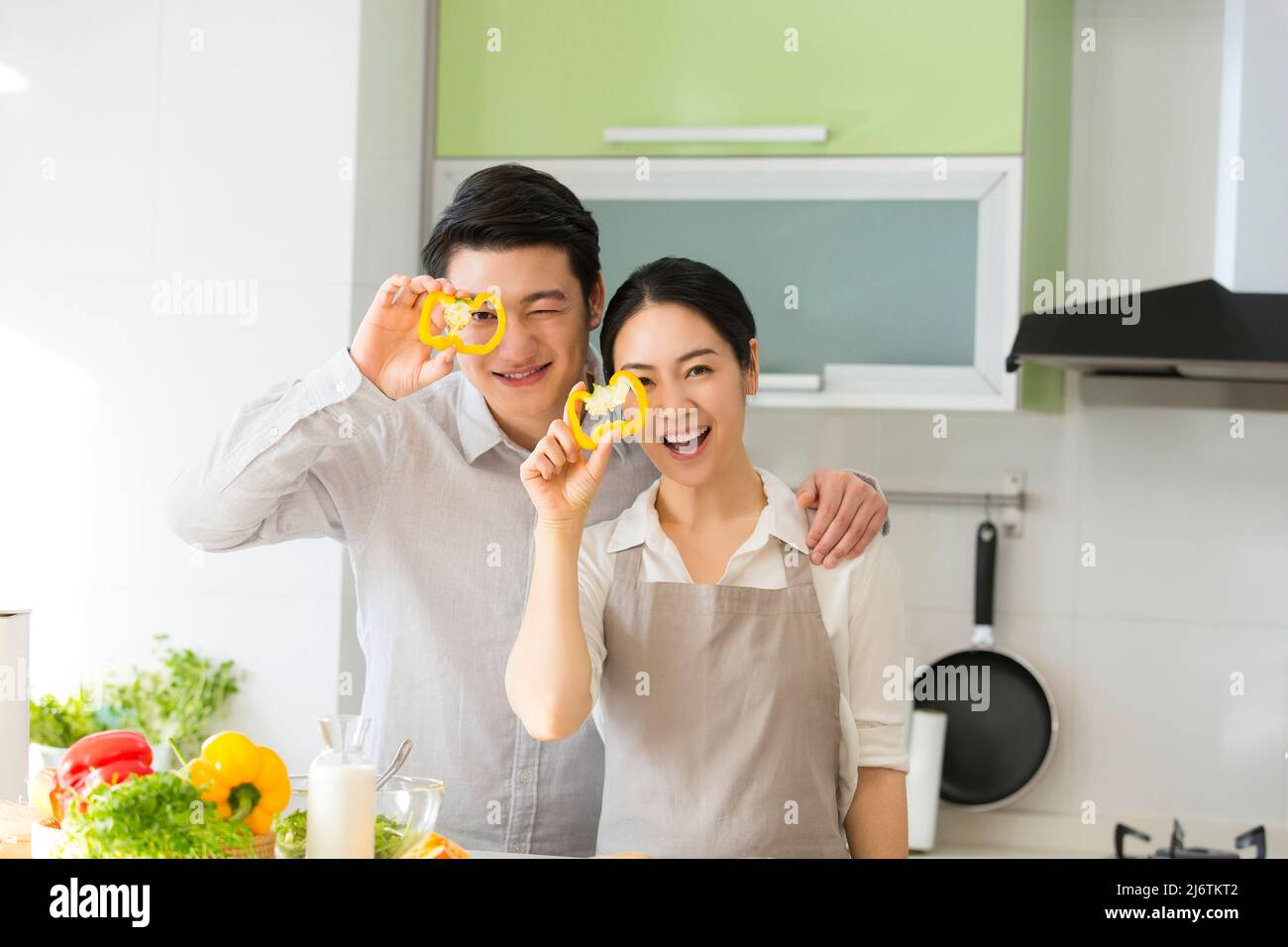 Dans la cuisine familiale, un jeune couple qui apprécie la cuisine ensemble en prenant des tranches de poivron jaune - photo de stock Banque D'Images