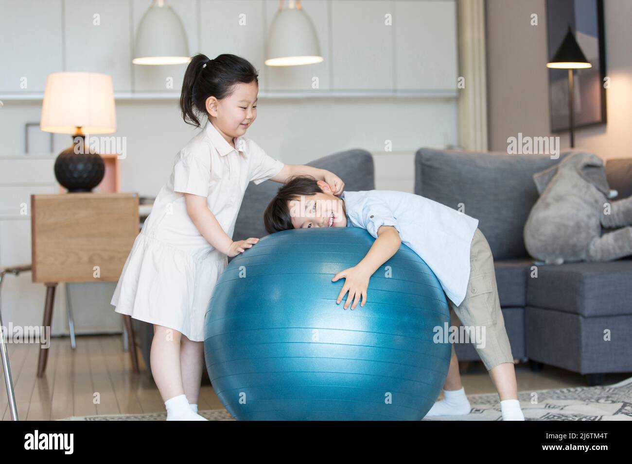 Une petite fille et un petit garçon jouant intimement sur la balle d'exercice dans le salon - photo de stock Banque D'Images