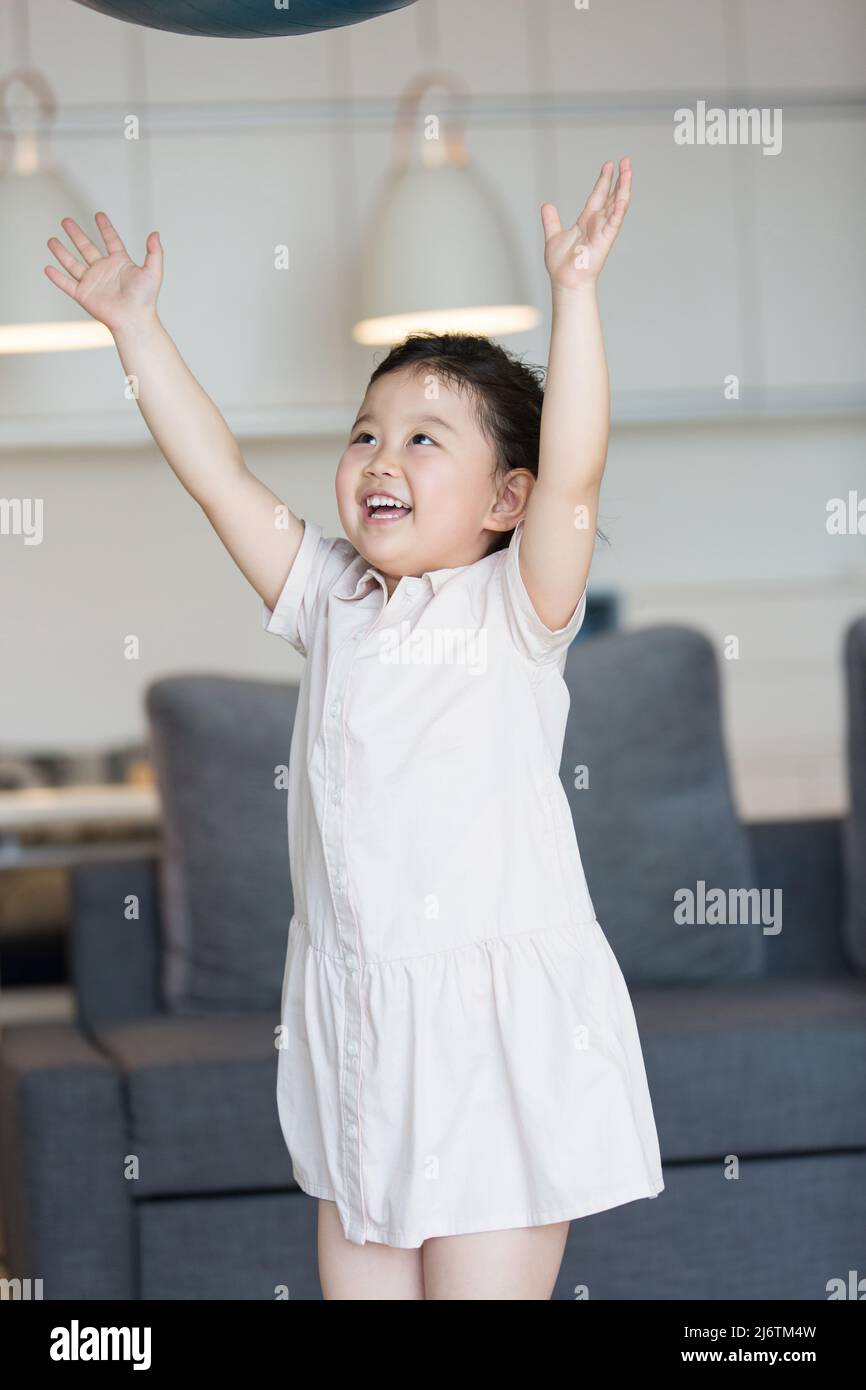 Une petite fille lance le ballon de fitness avec anticipation - photo de stock Banque D'Images