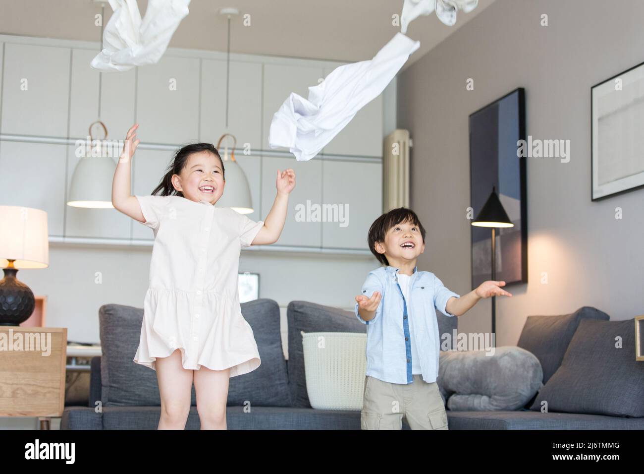 Près du canapé du salon, les frères et sœurs lancinaient leurs vêtements dans l'air - photo de stock Banque D'Images