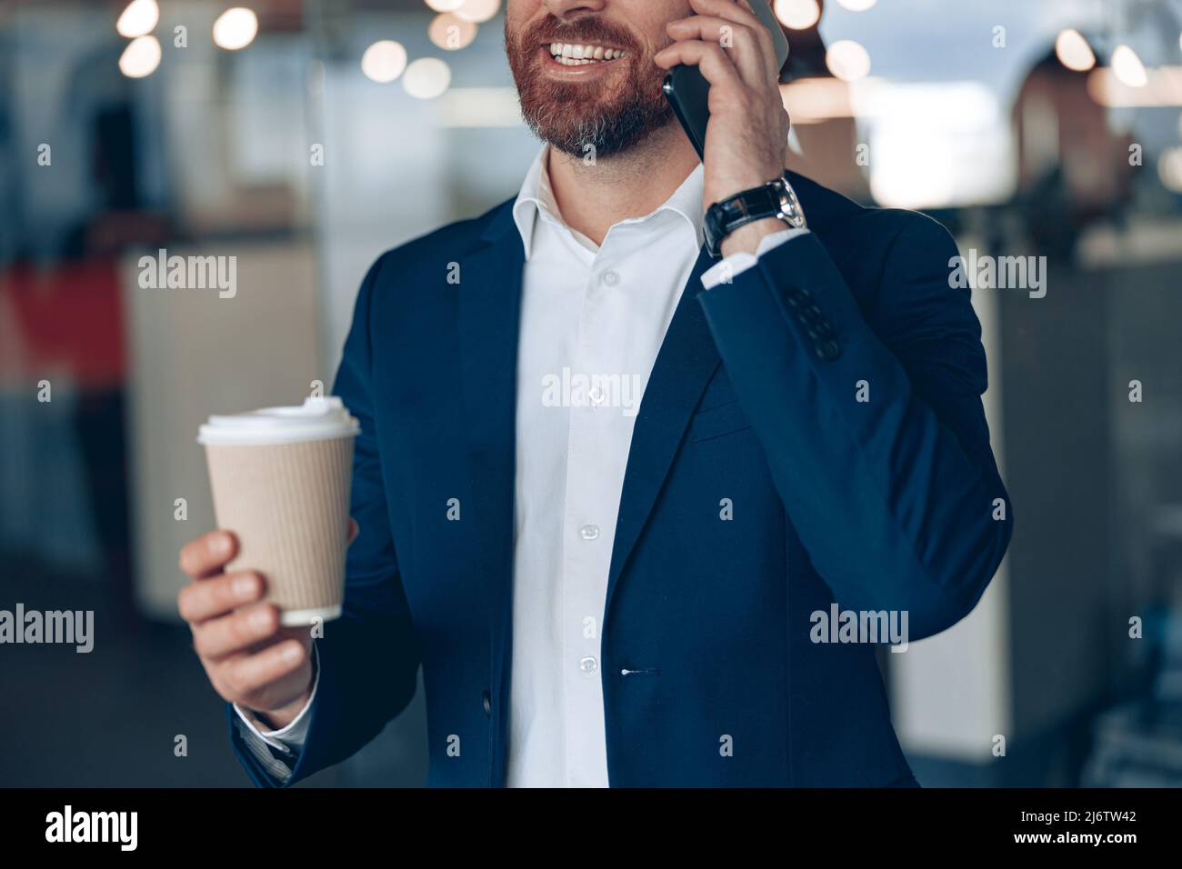 Gros plan sur un homme d'affaires souriant avec une tasse à café à emporter, parlant au téléphone portable avec un partenaire d'affaires Banque D'Images