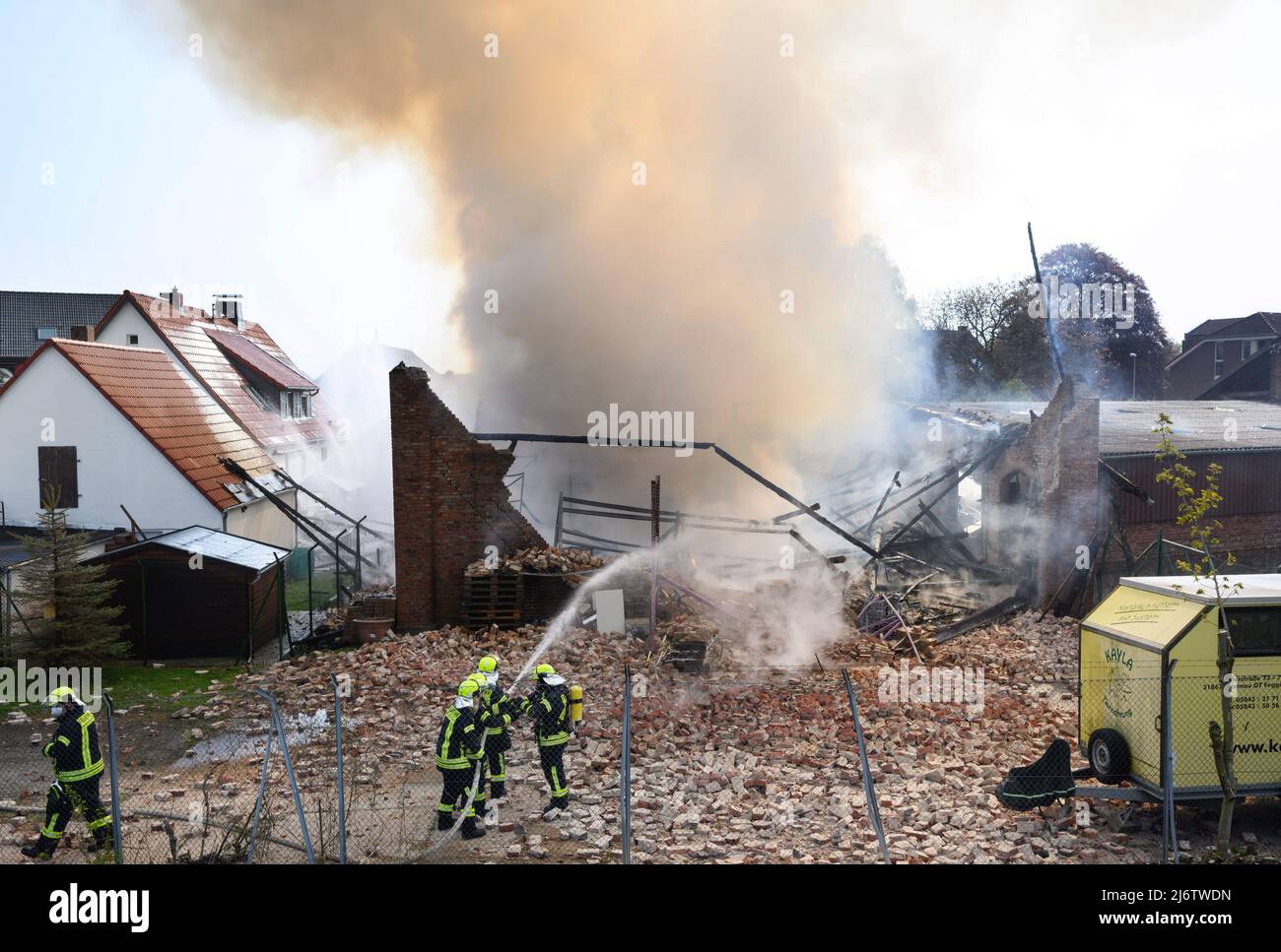 04 mai 2022, Basse-Saxe, Gehrden: Les pompiers éteignent un incendie dans une ferme de la région de Hanovre. Une grange dans laquelle, entre autres choses, une entreprise de construction de stand d'exposition opératait, brûlée au sol le matin. Le nuage de fumée pourrait être vu pendant des kilomètres. Photo: Julian Stratenschulte/dpa Banque D'Images