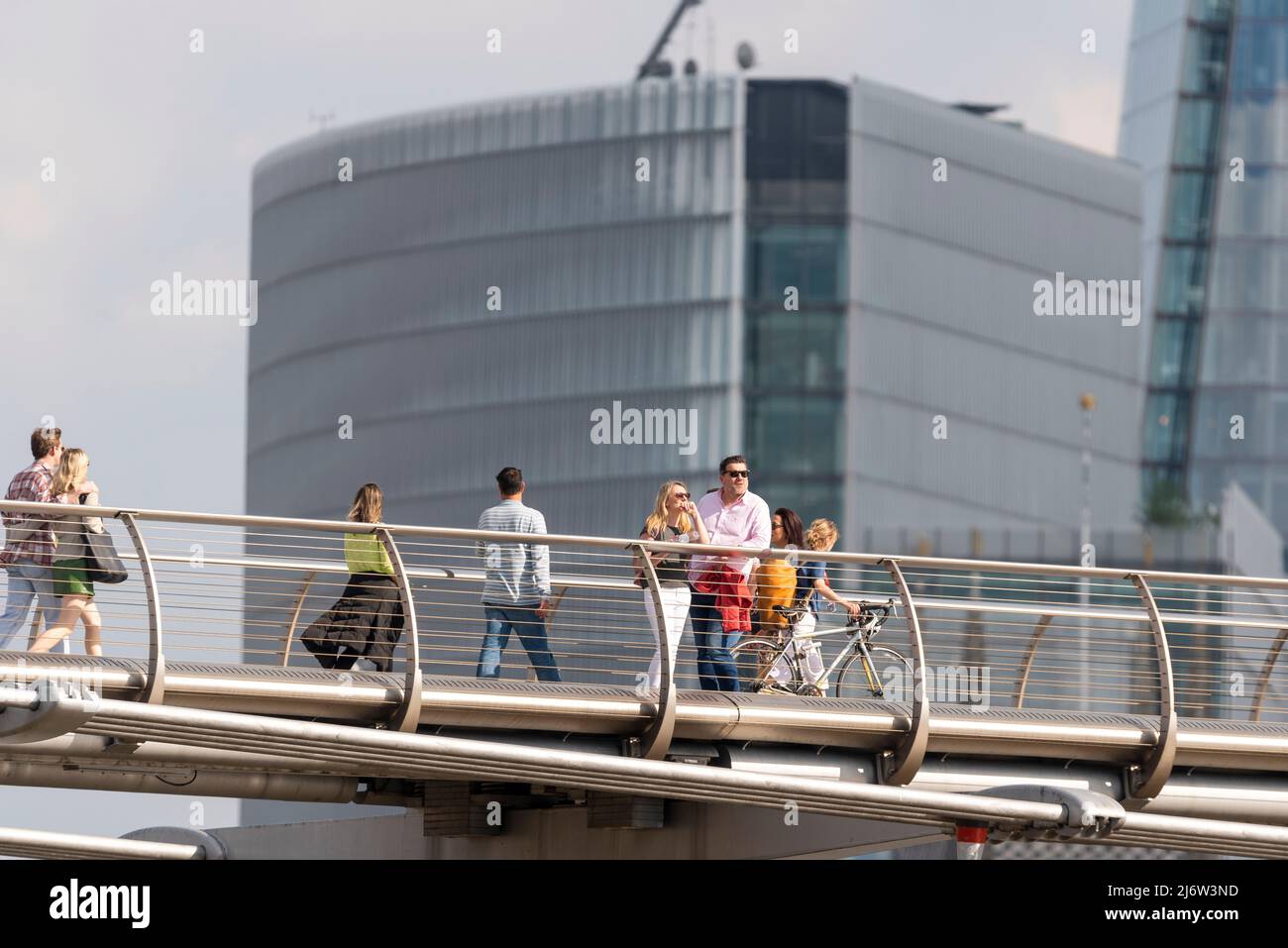 Personnes traversant le Millennium Bridge au-dessus de la Tamise, Londres, Royaume-Uni, en face de hauts développements. Une pause pour voir les sites Banque D'Images
