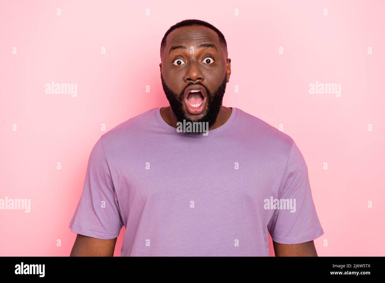 Photo de choqué funky Guy habillé violet t-shirt ouvert bouche grands yeux isolé couleur rose fond Banque D'Images