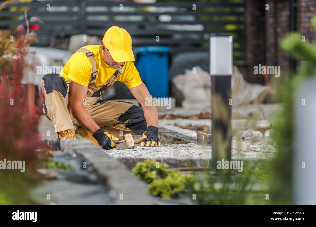Travailleur de l'aménagement paysager caucasien dans son jardin d'arrière-cour du bâtiment de 40s Granite Bricks Path. Industrie résidentielle de l'aménagement paysager. Banque D'Images