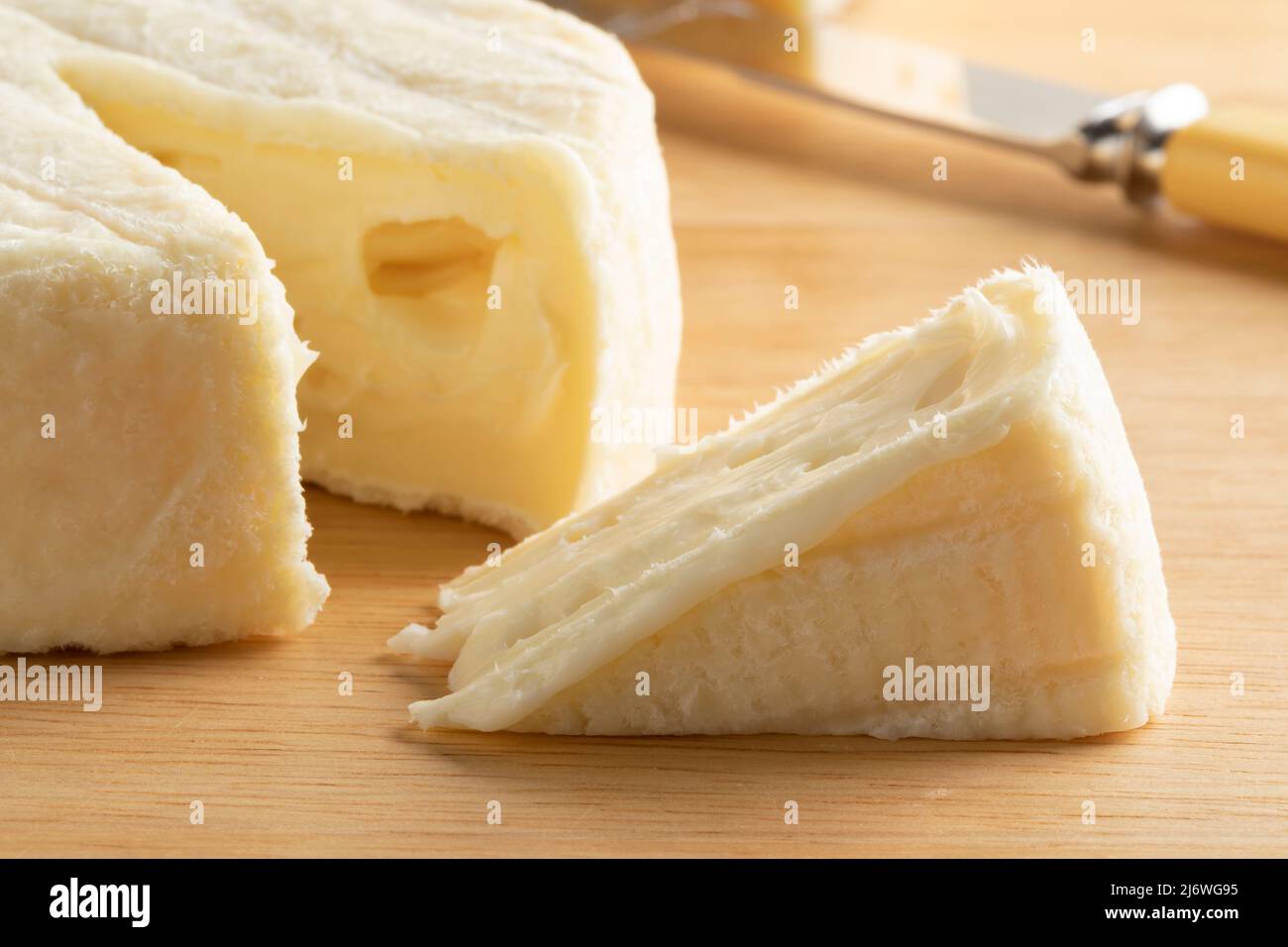Un morceau de fromage Acacia français et un morceau sur une planche à découper en gros plan Banque D'Images