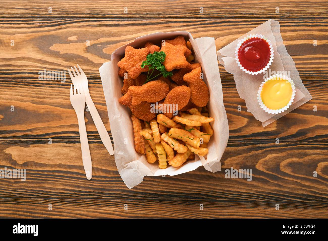 Fish and Chips, restauration rapide britannique. Bâtonnets de poisson avec frites sur une assiette en papier à emporter sur un fond de table en bois. Traditionnel anglais Banque D'Images
