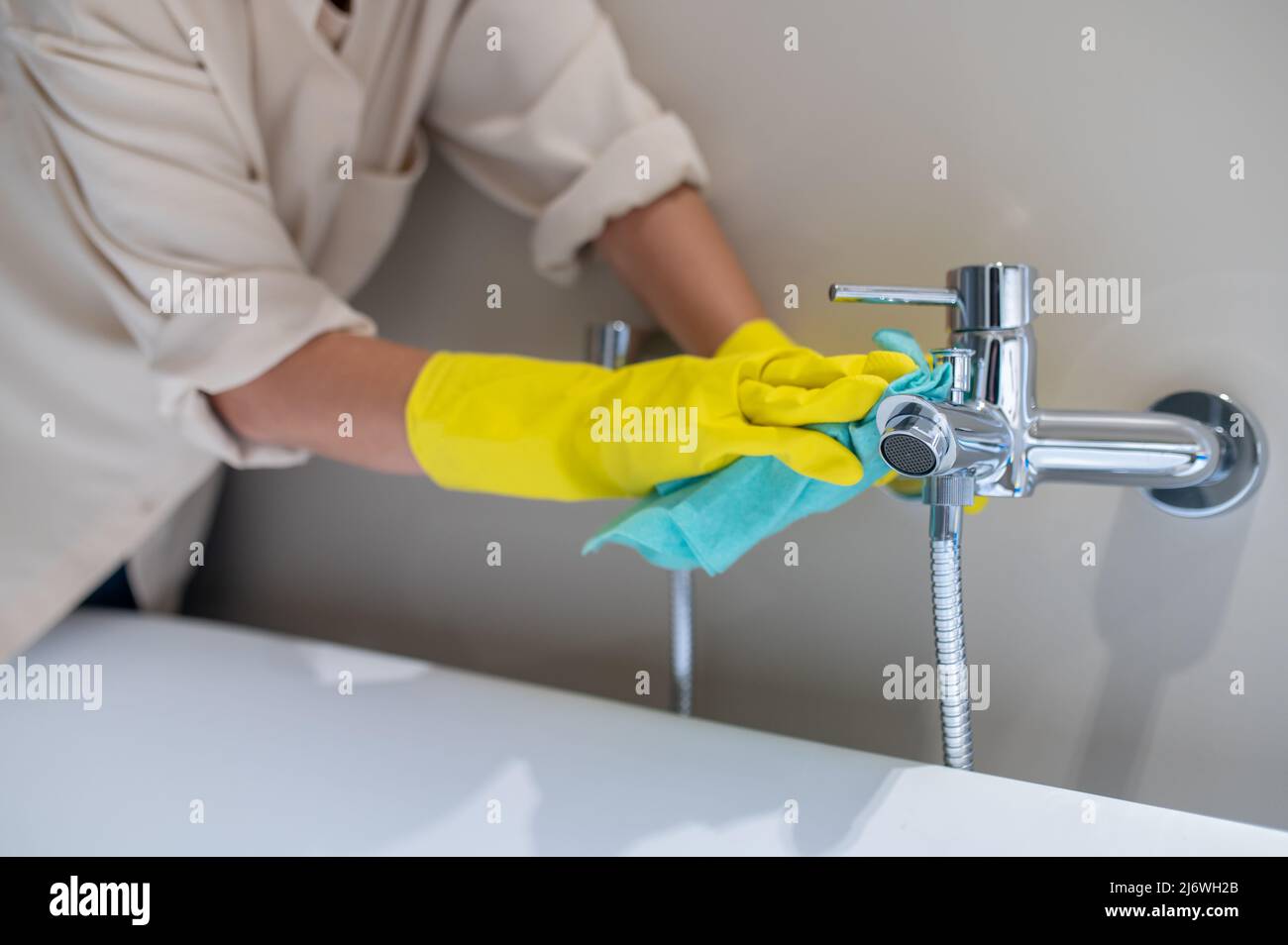 Une femme de service à polir le robinet dans la salle de bains Banque D'Images