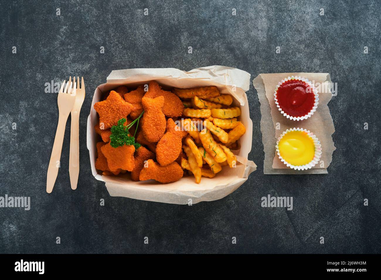 Fish and Chips, restauration rapide britannique. Bâtonnets de poisson avec frites sur une plaque de papier à emporter sur fond de béton ancien sombre. Traditionnel anglais authe Banque D'Images