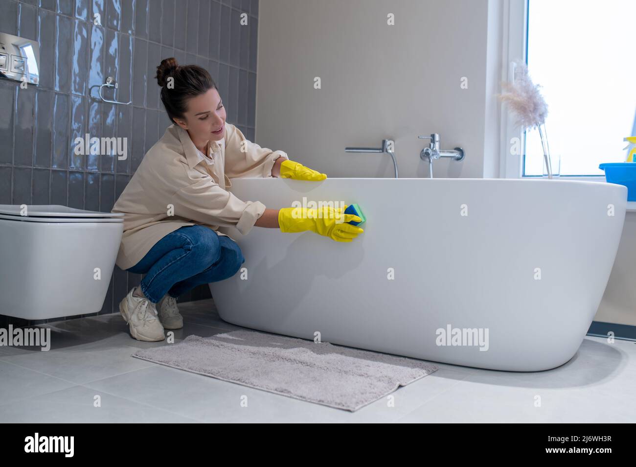 Une femme faisant le nettoyage à la maison et la désinfection de la salle de bains Banque D'Images