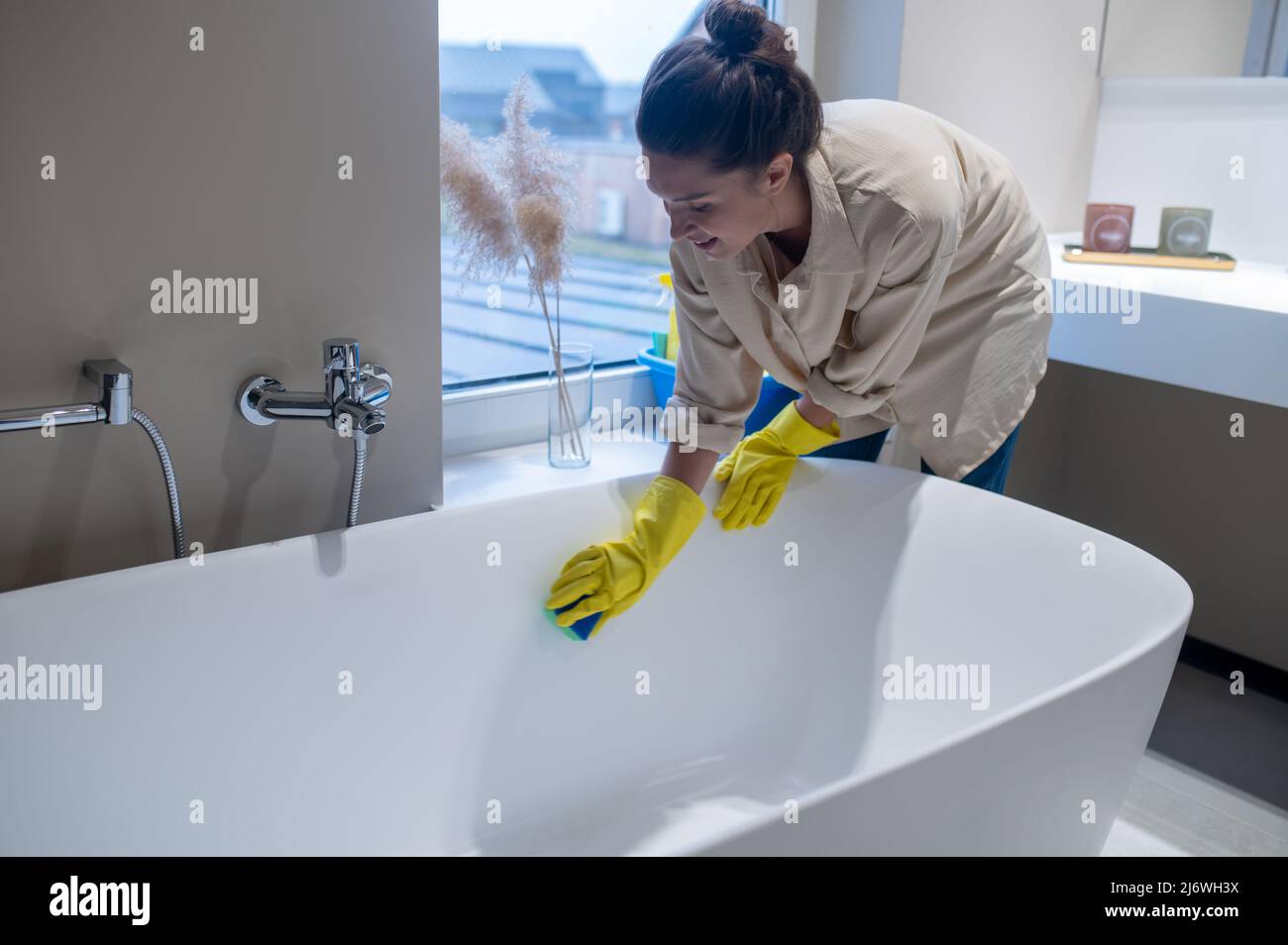 Une femme faisant le nettoyage à la maison et la désinfection de la salle de bains Banque D'Images