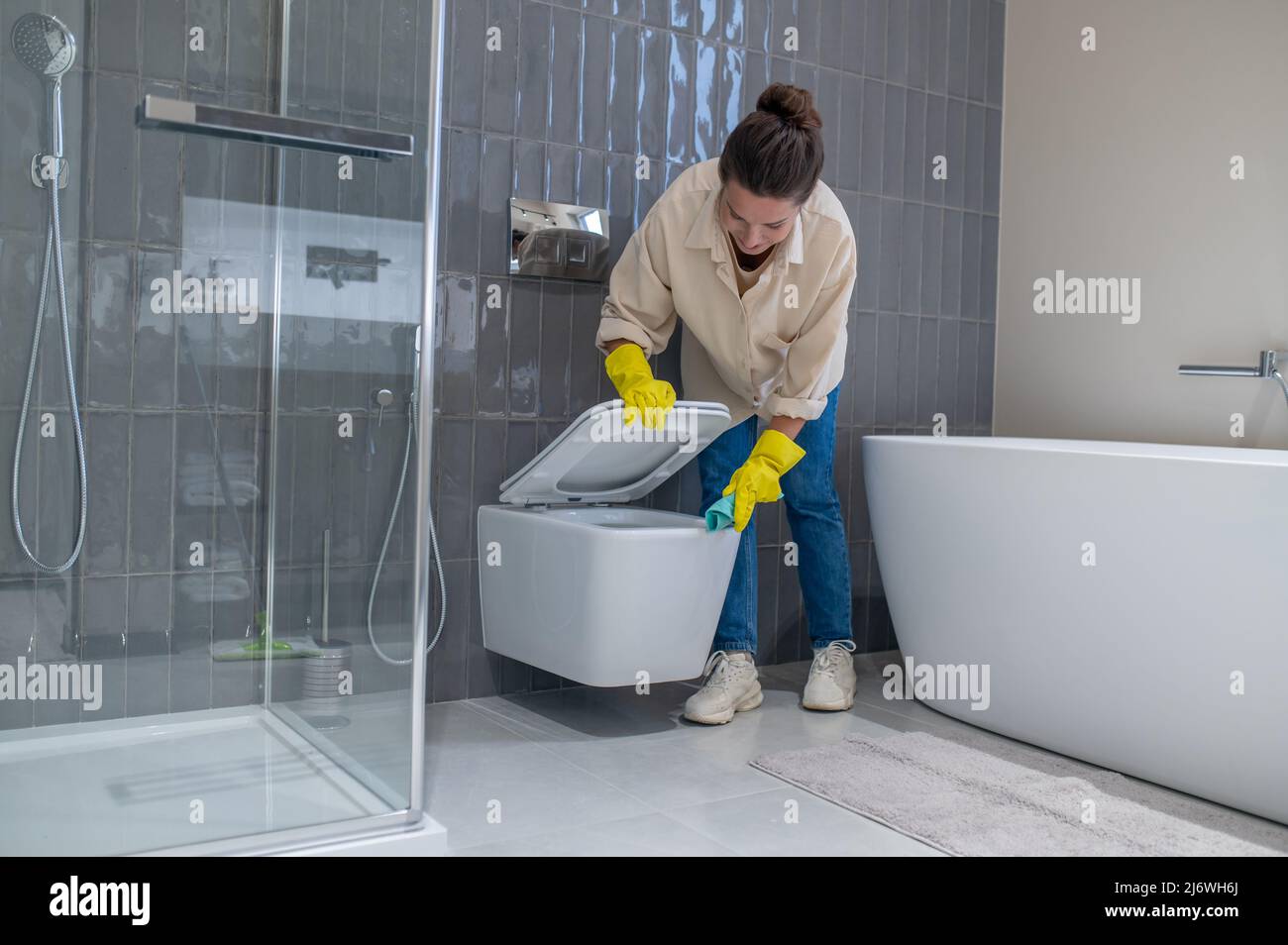 Yung femme de ménage avait l'air occupée pendant le nettoyage dans la salle de bains Banque D'Images