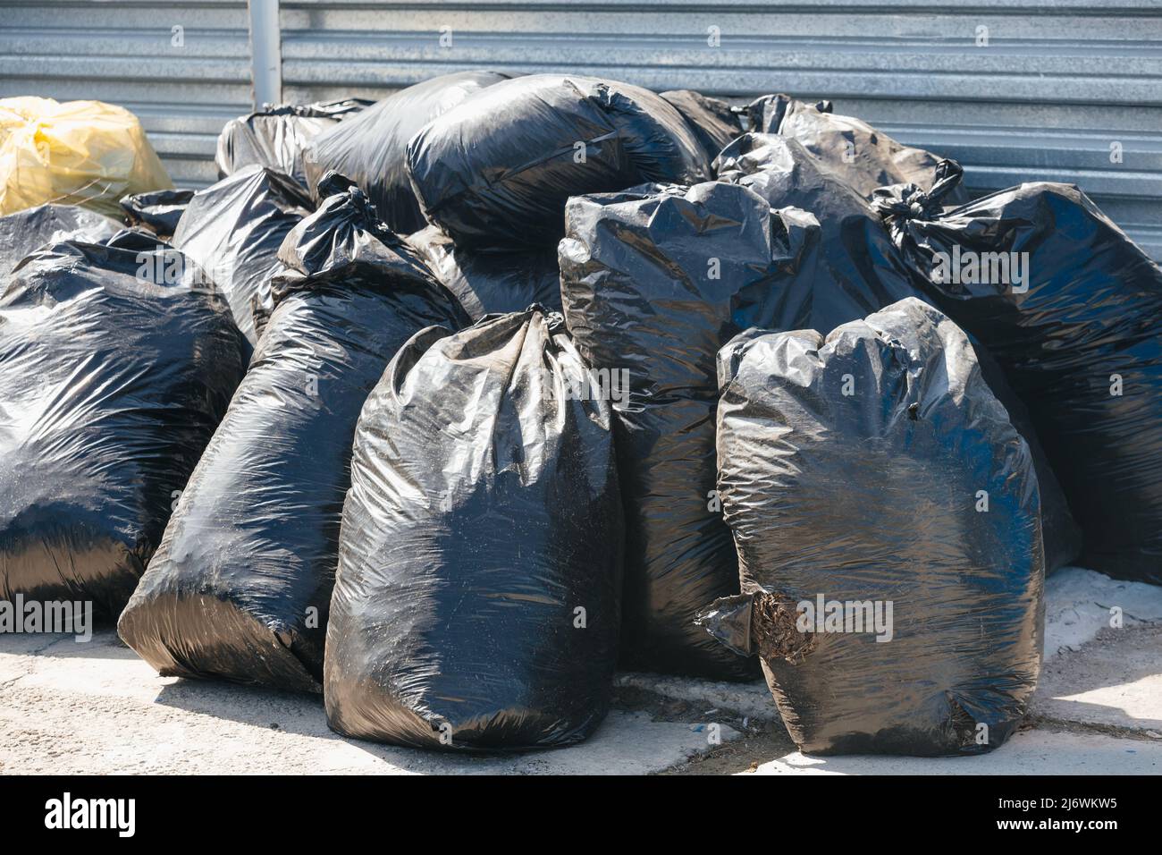 Sacs en plastique noir avec ordures. Nettoyage du territoire de la pollution et des déchets. Problème environnemental. Arrière-plan. Banque D'Images