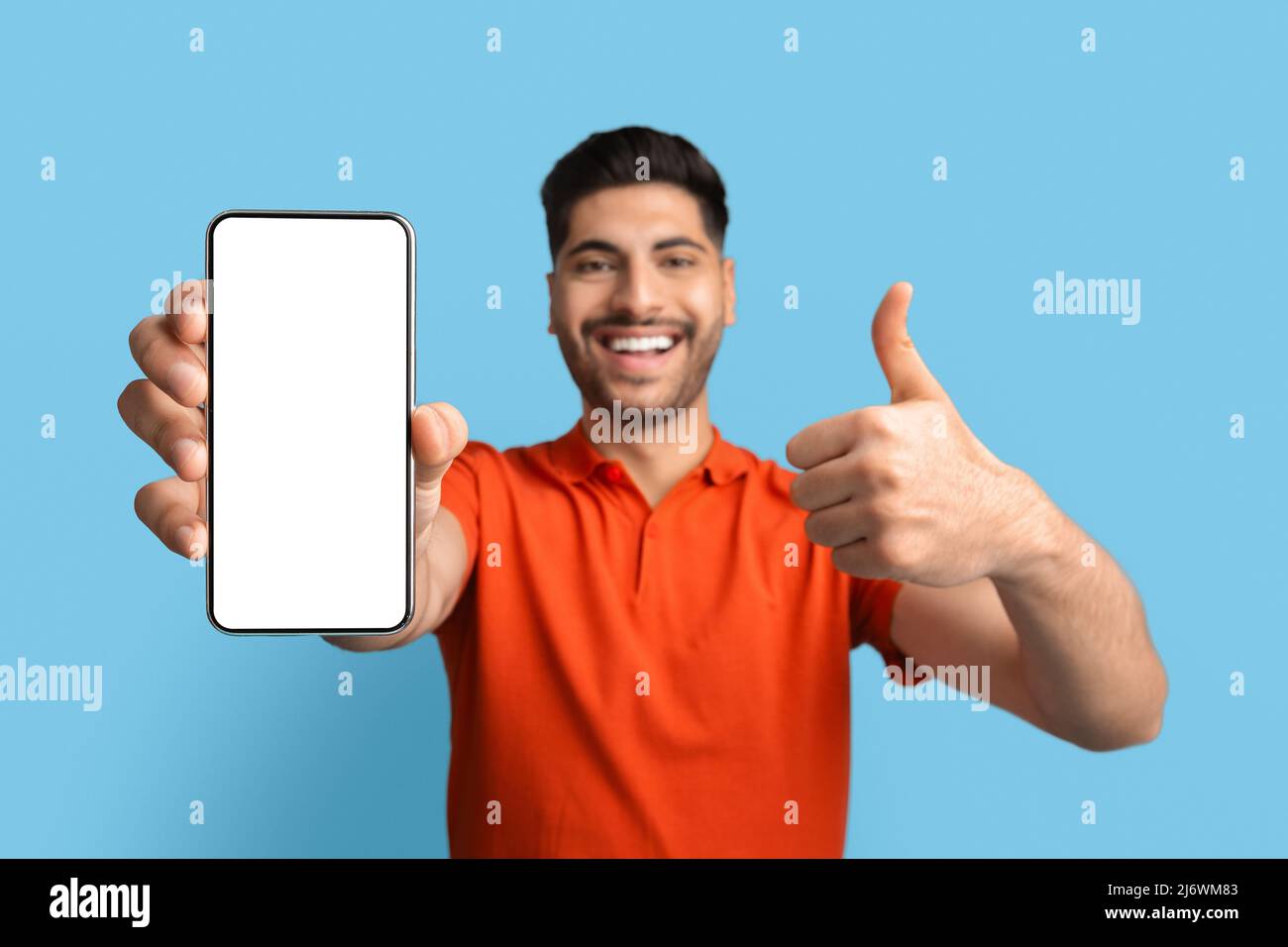 Arab Man montrant un smartphone vierge avec écran blanc et un coup de pouce Banque D'Images