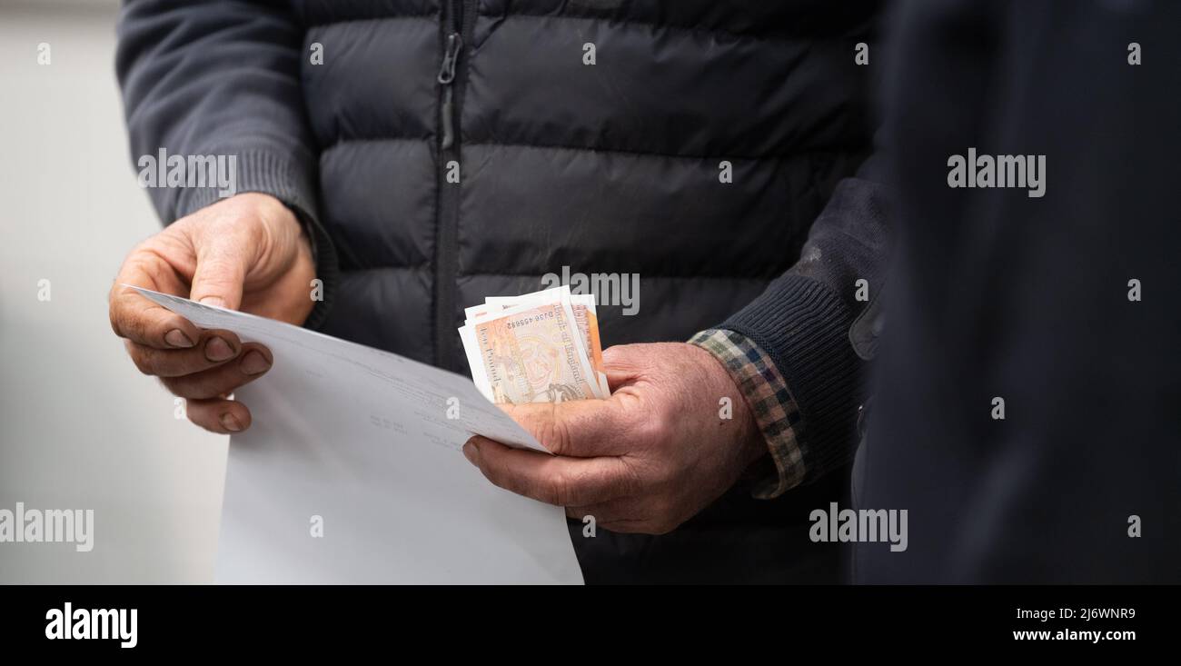 Agriculteur avec de l'argent dans ses mains après une vente aux enchères de marché. Cumbria, Royaume-Uni. Banque D'Images