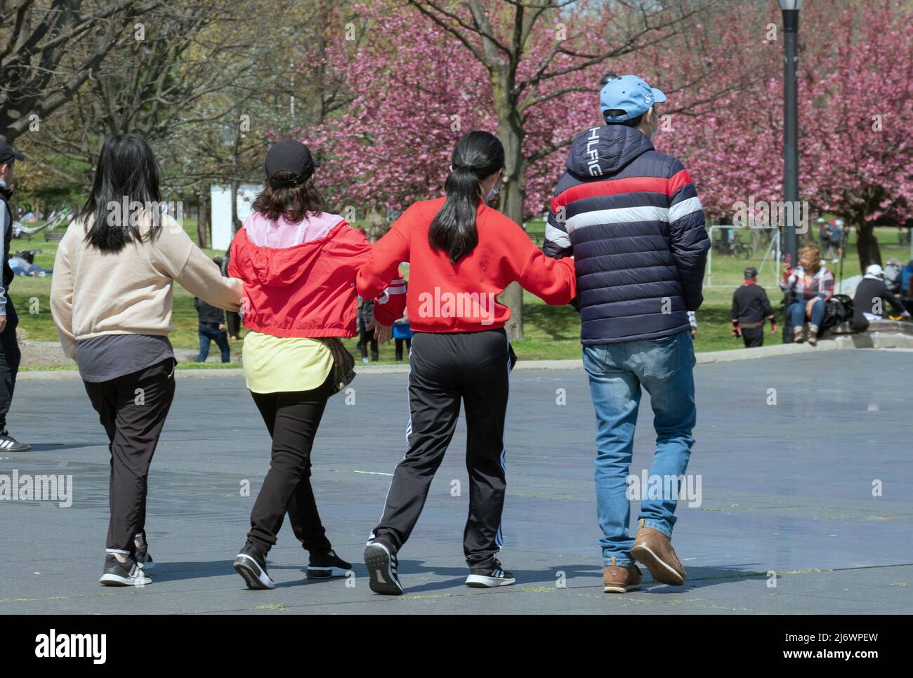 Quatre Américains asiatiques marchent bras-à-bras dans le parc de Flushing Meadows Corona un dimanche de printemps doux. À Queens, New York. Banque D'Images