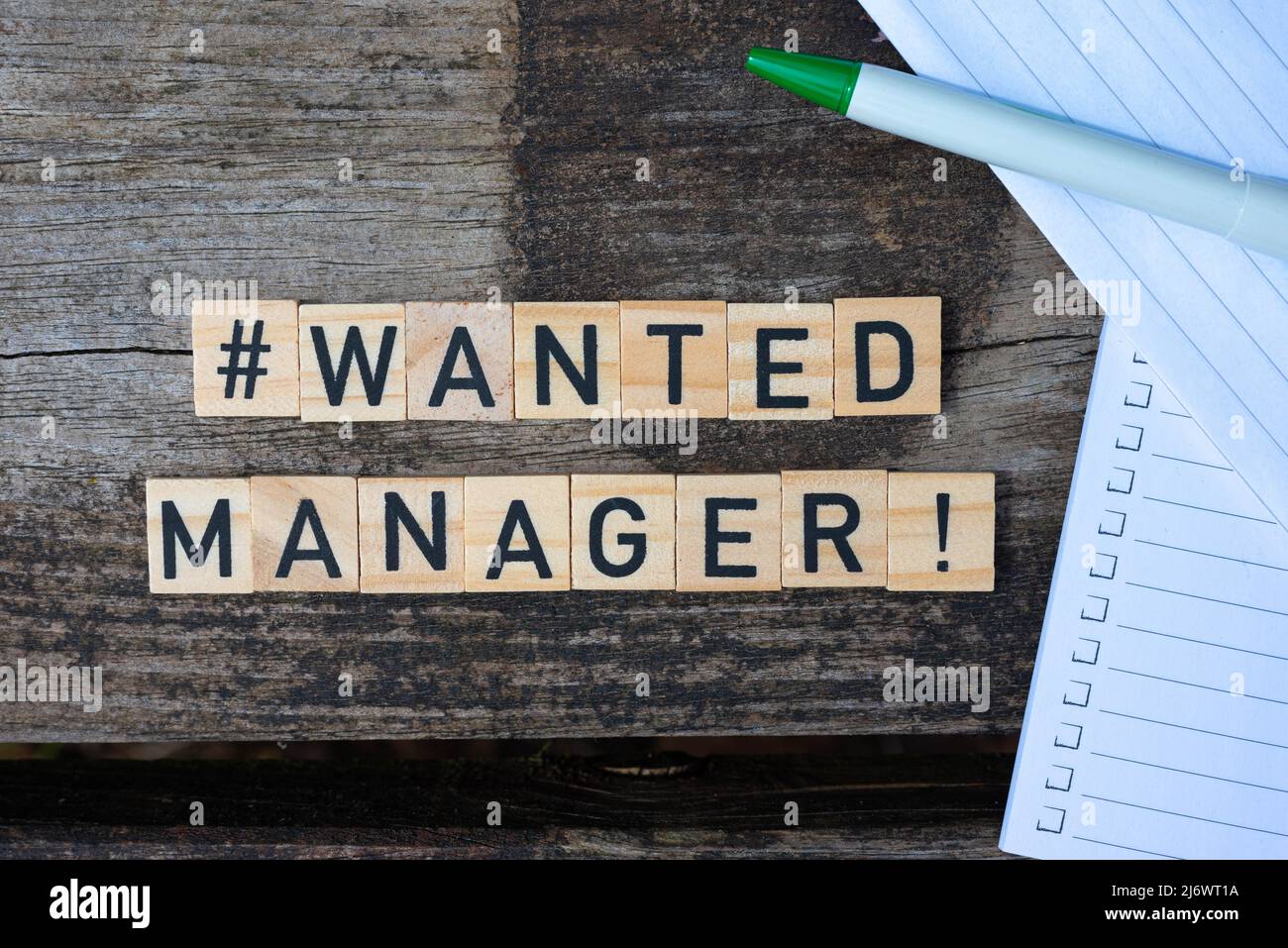 Blocs de jouets en bois avec le texte Wanted Manager dessus avec stylo et papier en arrière-plan. Photo parfaite pour les recruteurs, les RH, les entreprises, les entreprises Banque D'Images